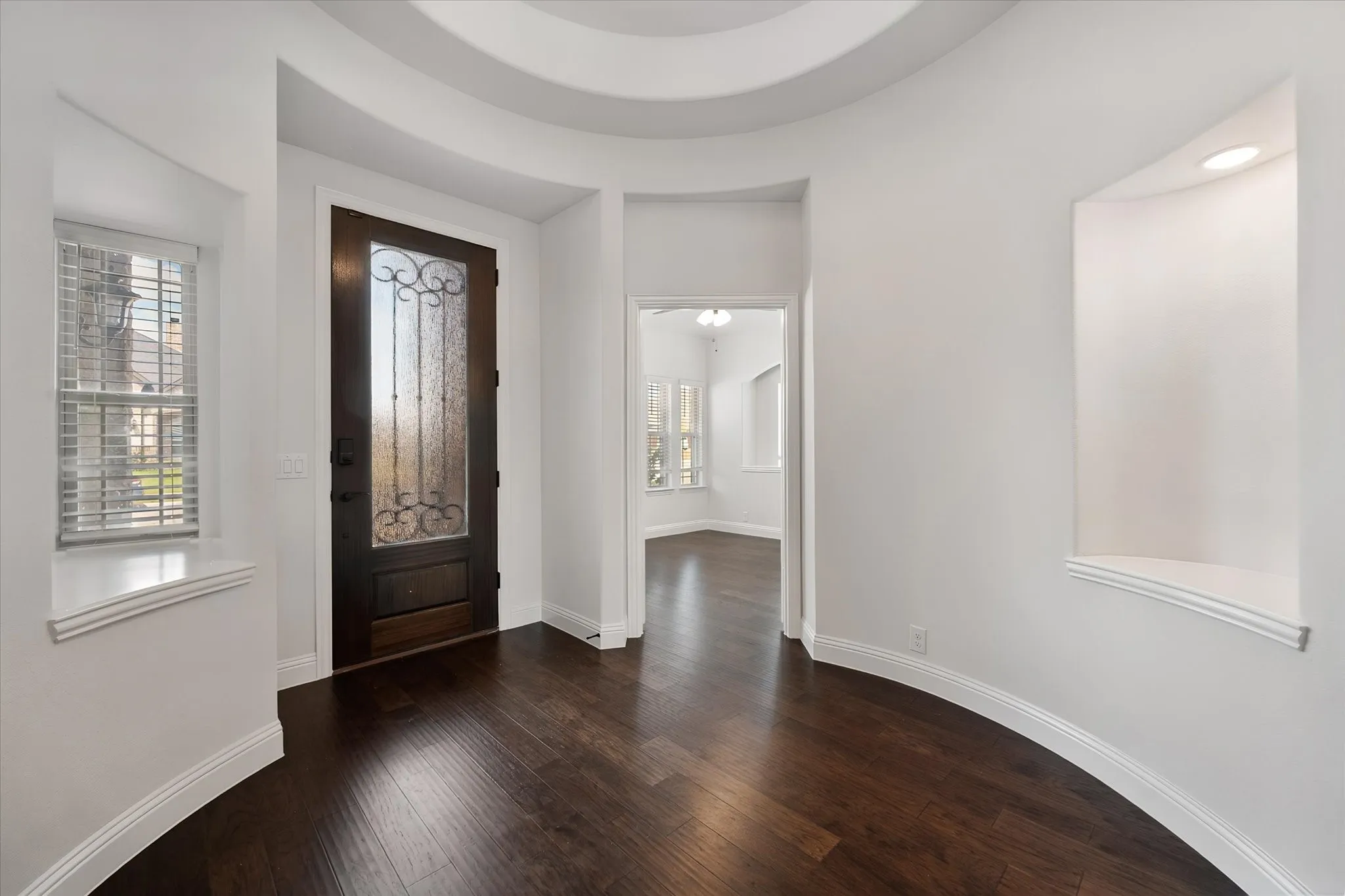 This is the moment you walk in the front door — feel that curved wall? It's such a unique architectural detail, and the dark wood floors set the tone right away for the whole downstairs.