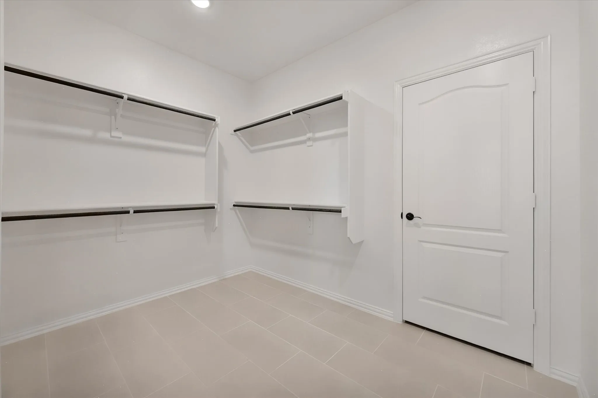 The primary walk-in closet — double hanging rods on both walls, so there's room for every season's wardrobe.