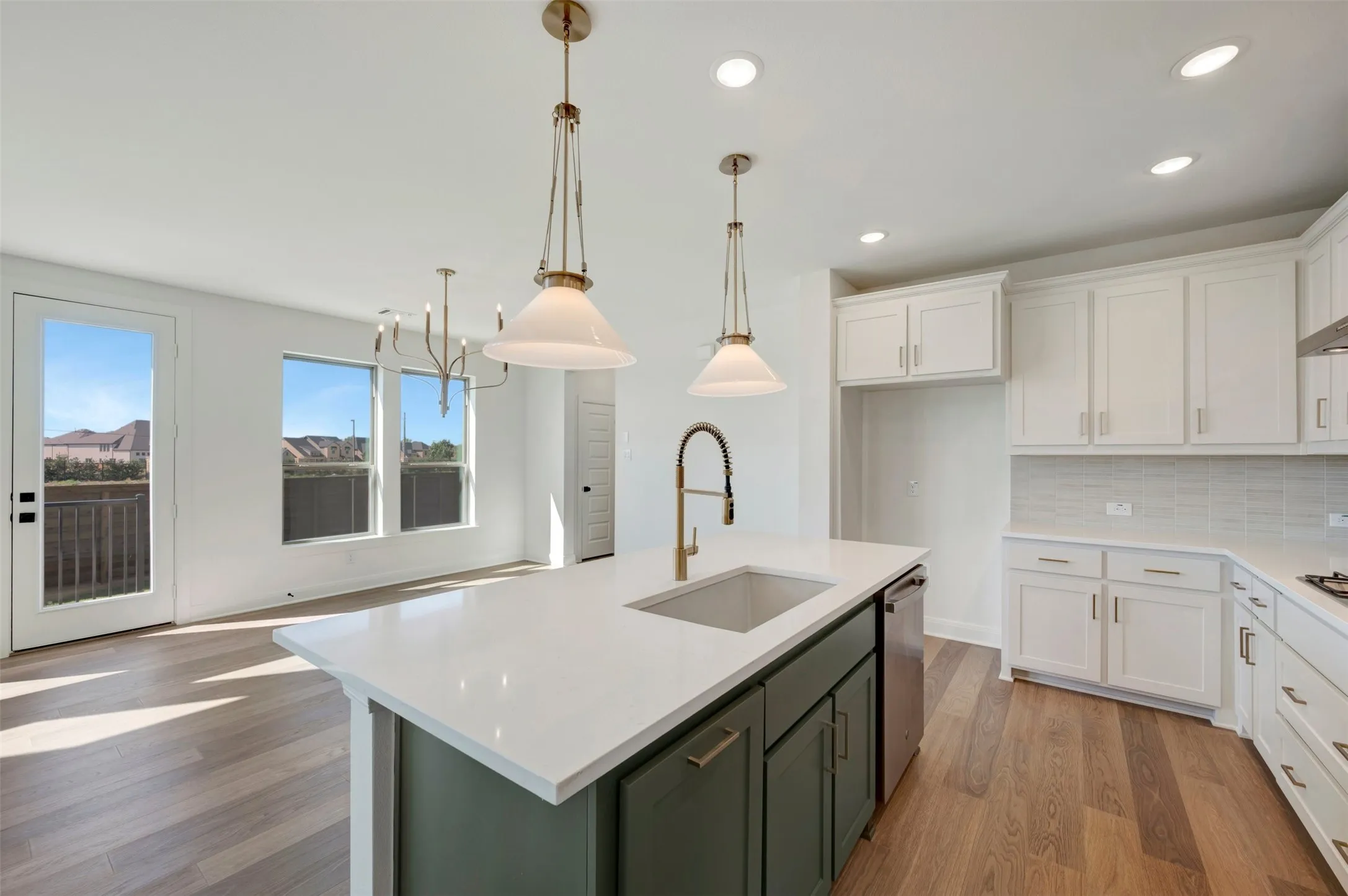 Kitchen featuring an island with a vessel sink and dual pendant lighting, white upper and lower cabinetry, white countertops, and a tiled backsplash