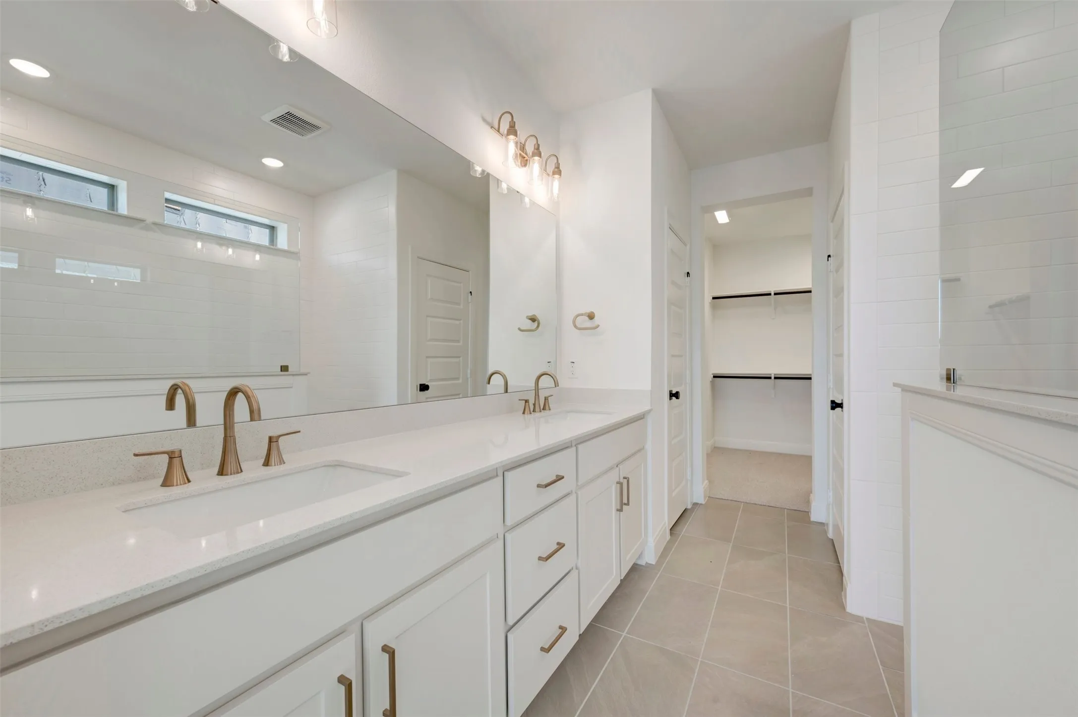 Dual vanity with undermount sinks, bronze finish fixtures, and white cabinetry