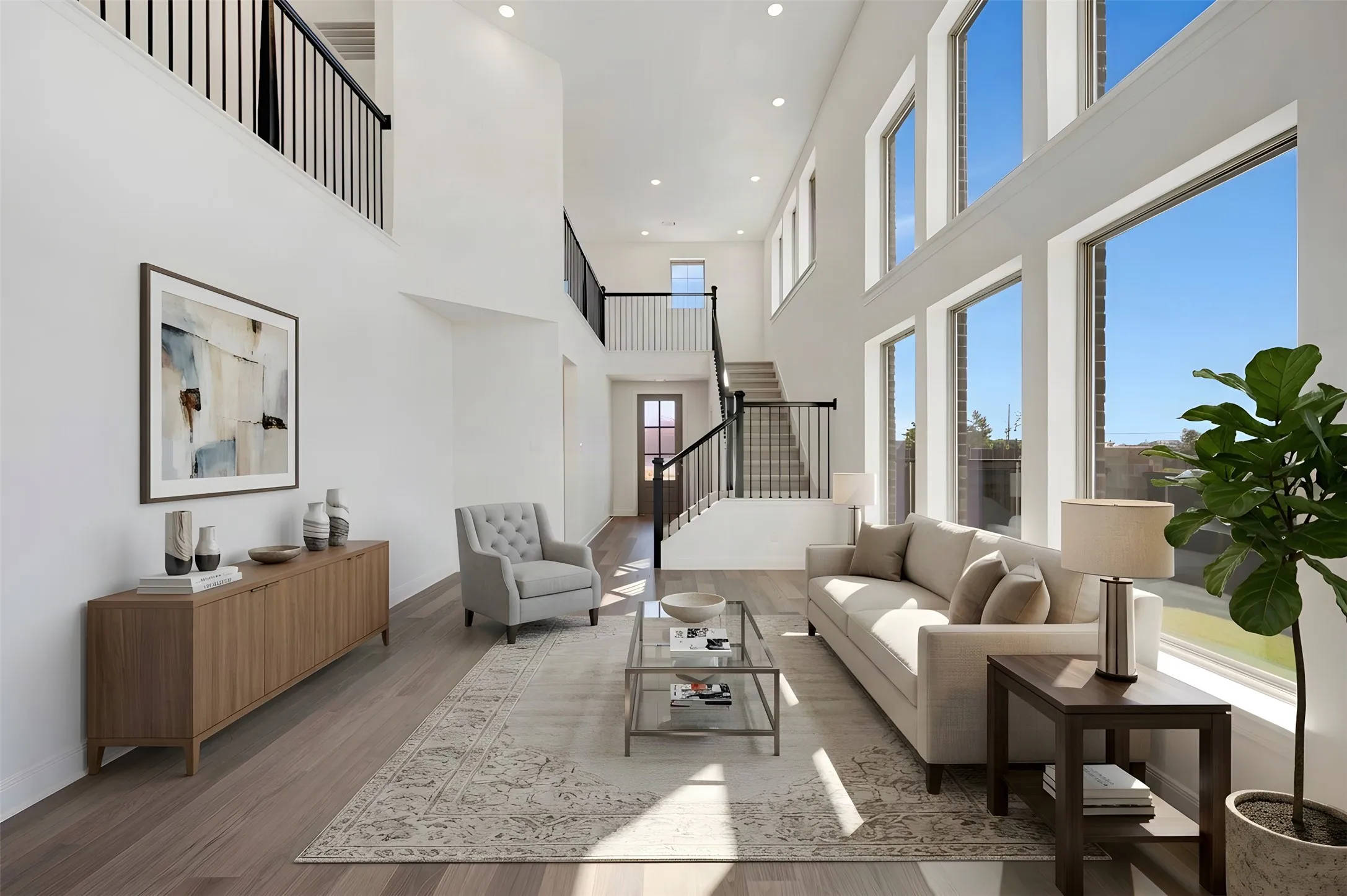 Two-story living area with soaring ceilings, expansive windows, wood-finish flooring, and a multi-level staircase with open railings