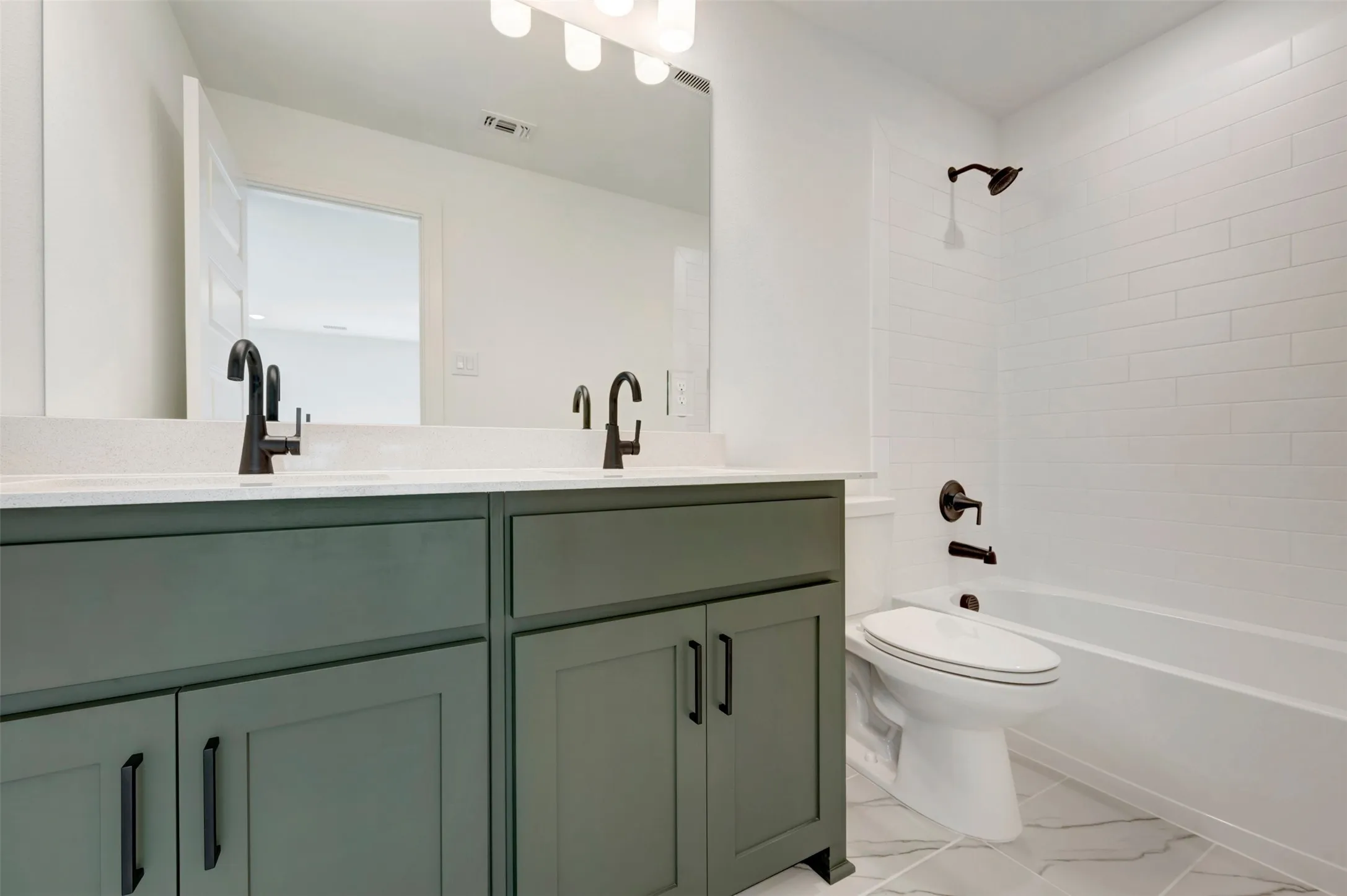 Dual vanity with dark green cabinetry and a light-toned countertop, featuring matte black fixtures