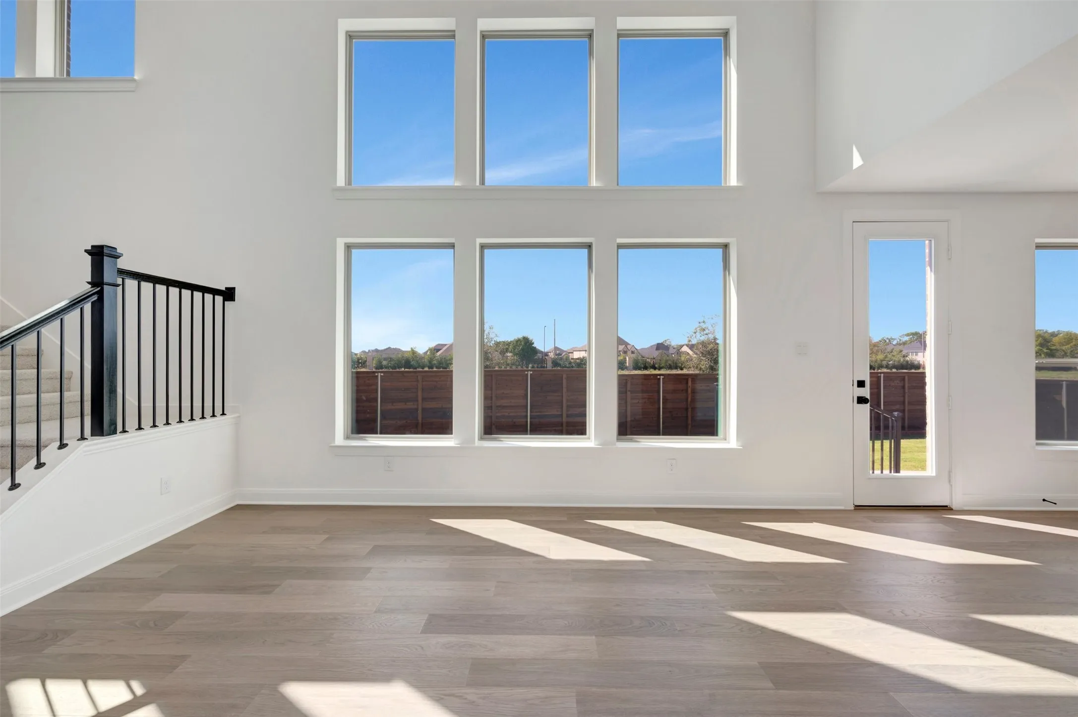 Two-story living area with high ceilings, wood-finish flooring, and multiple windows