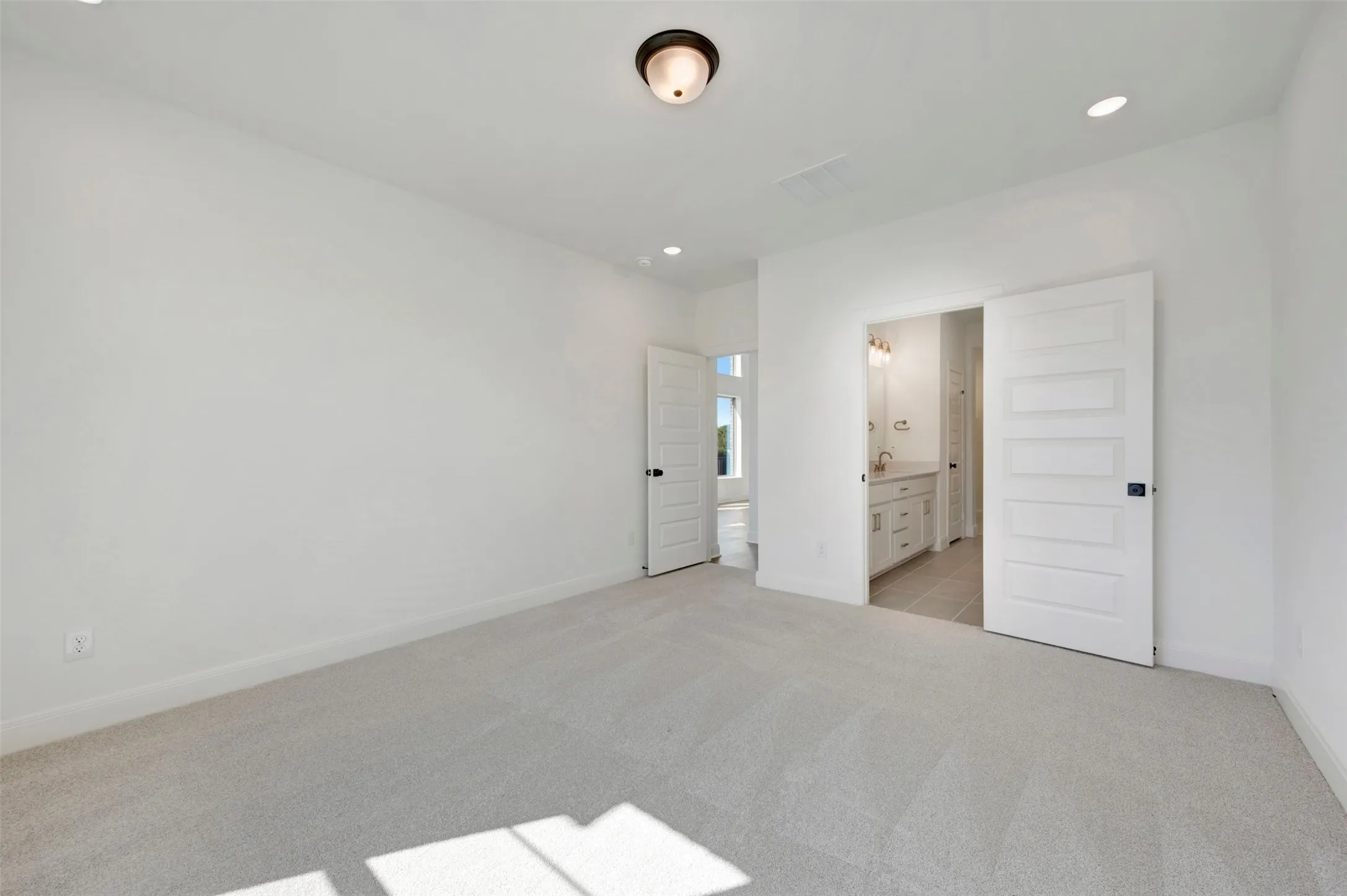Neutral-toned carpeting with recessed lighting and a ceiling-mounted light fixture