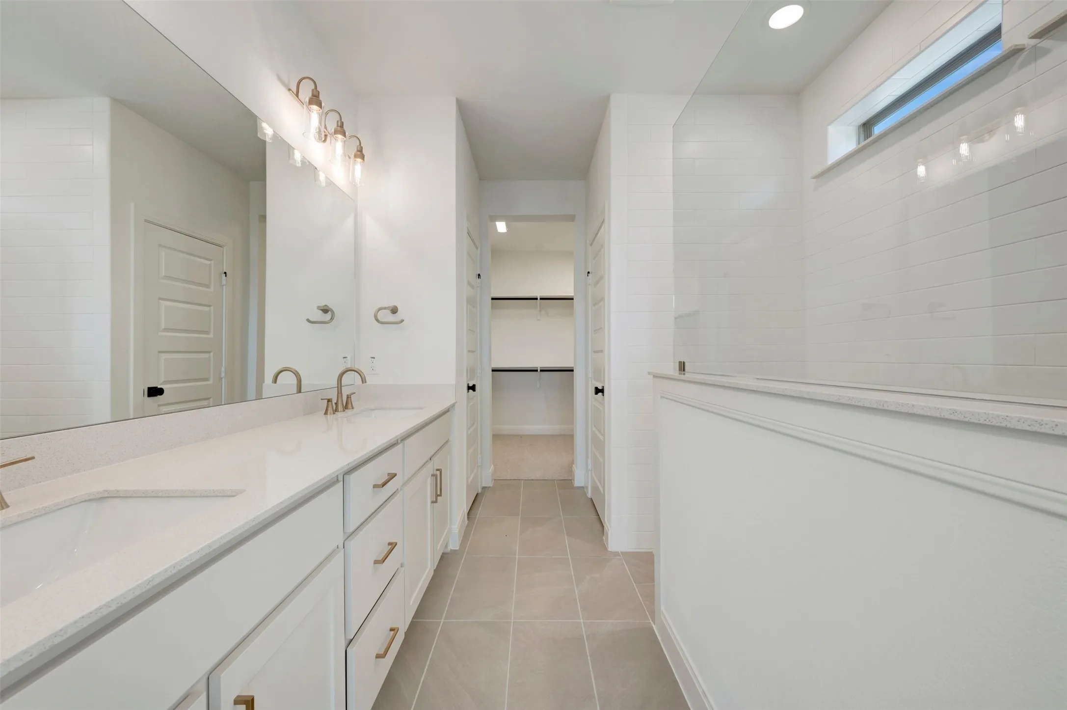 Double vanity with integrated sinks, white cabinetry, and gold-finish hardware