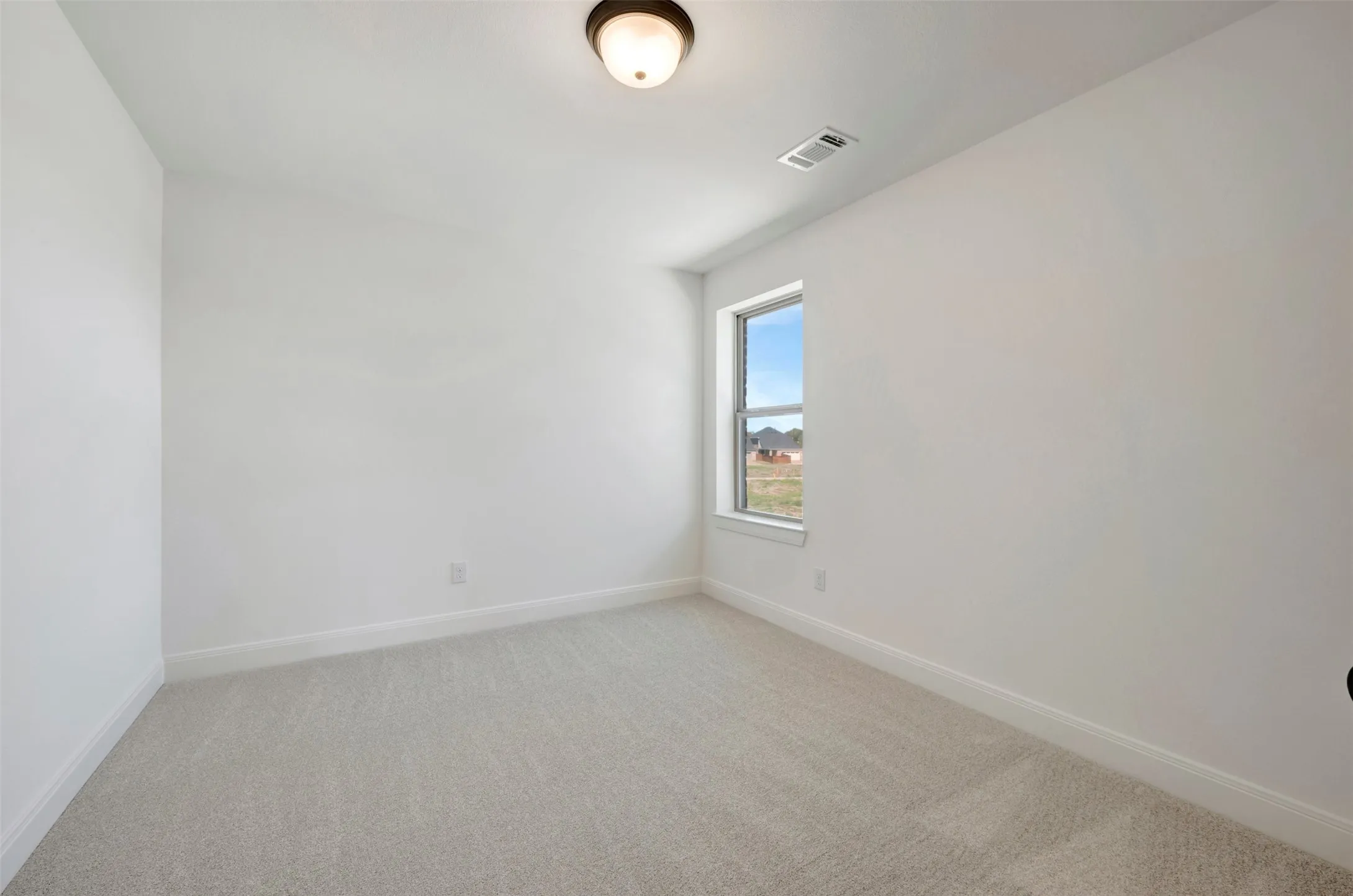 Recessed window with white trim, light-colored carpeting, white painted walls, and a flush-mount ceiling light fixture