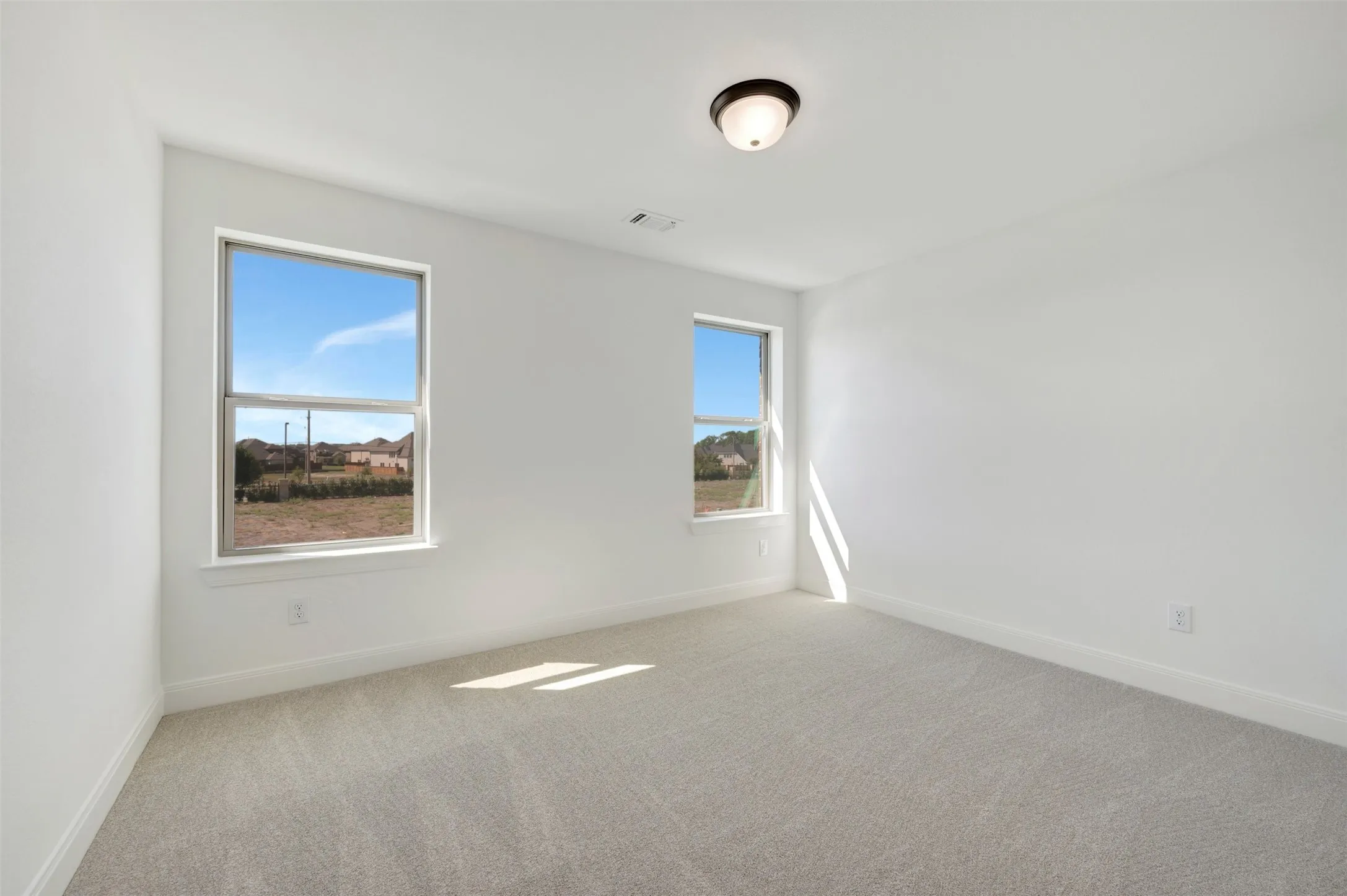 Neutral wall paint, light-toned carpet, and a ceiling-mounted light fixture