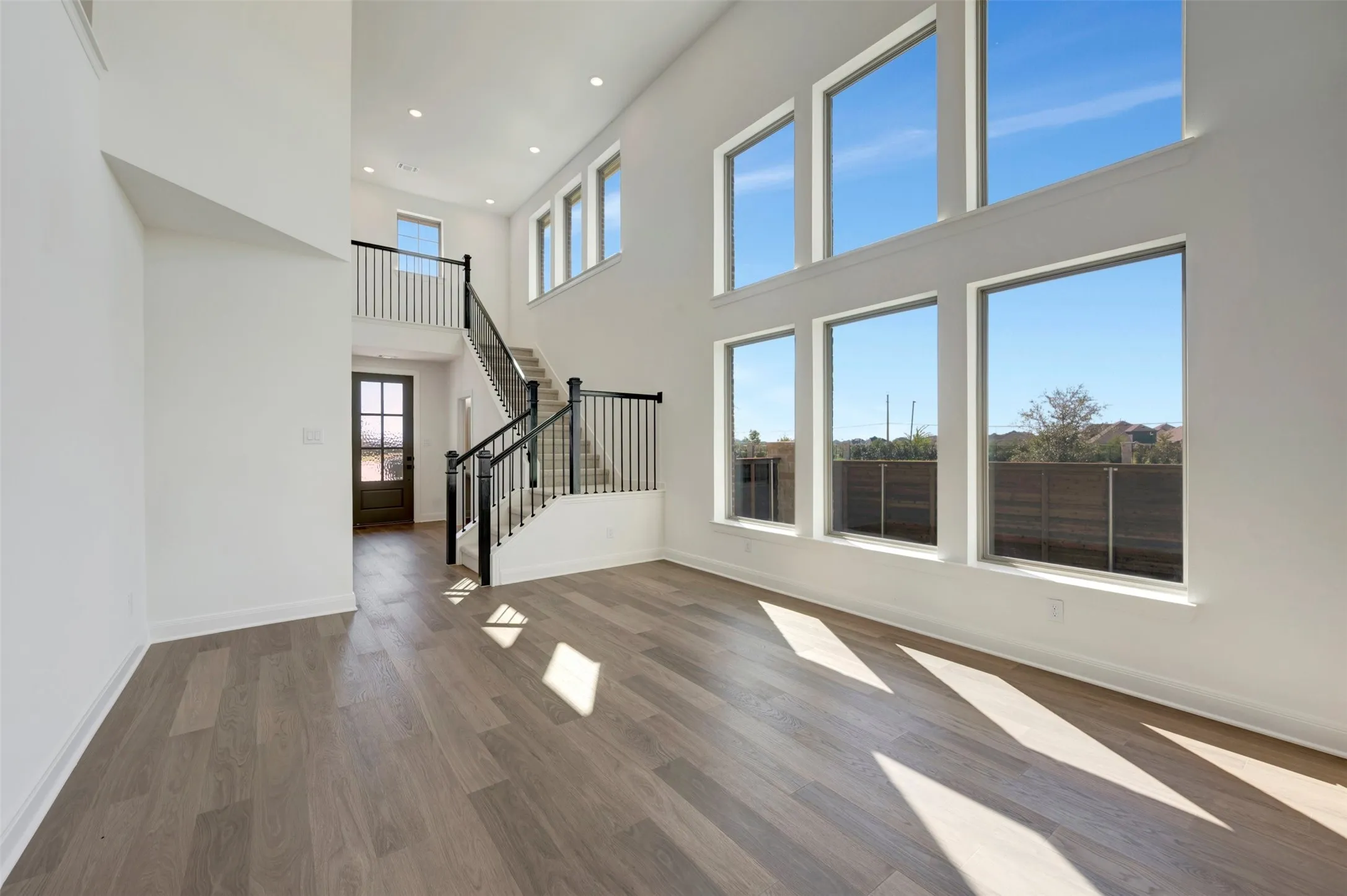 Vaulted ceiling, recessed lighting, wood-finish flooring, multi-pane windows, and a staircase with open balusters