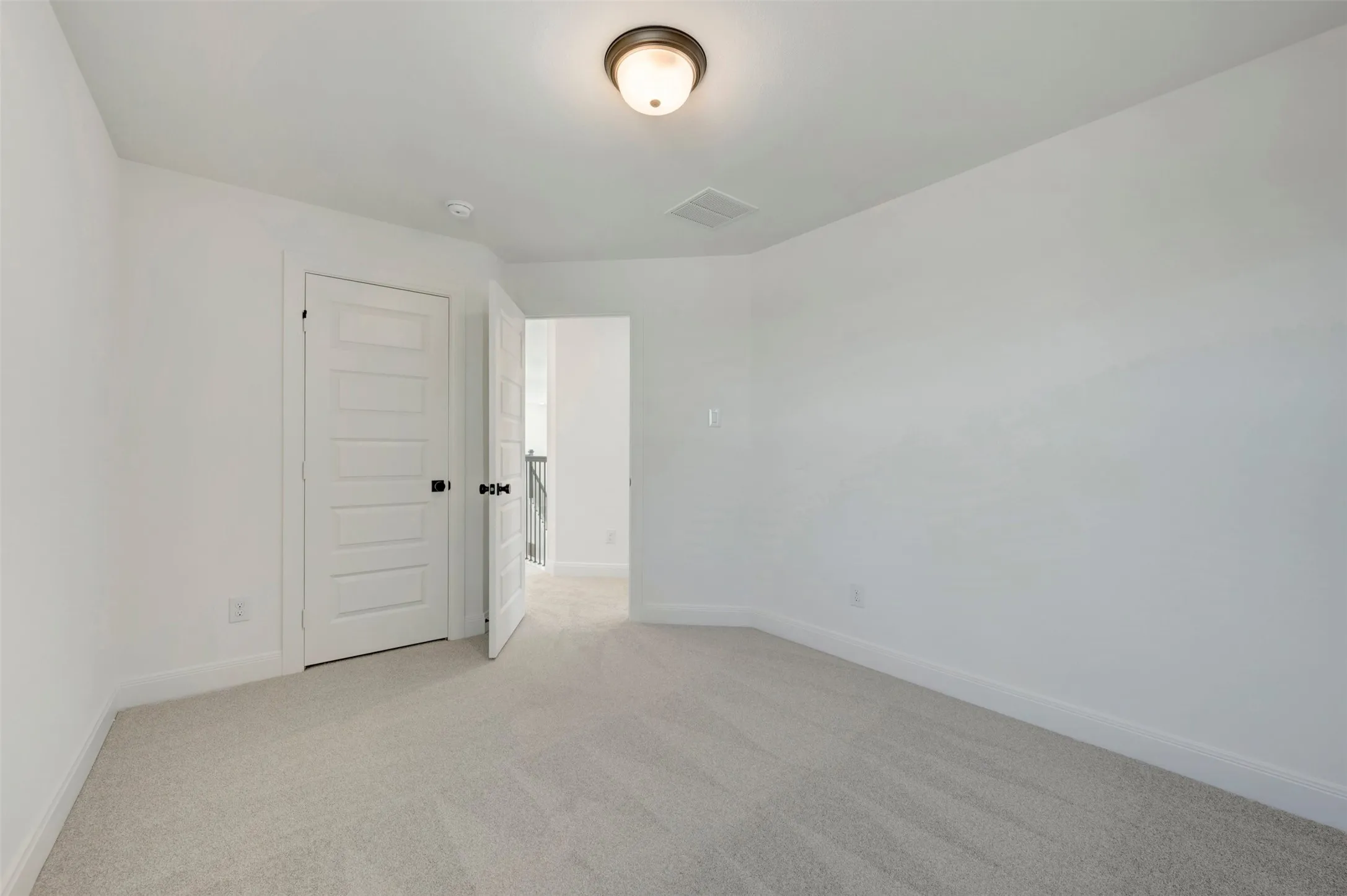 Neutral paint palette with light-colored carpet flooring, recessed lighting, and a paneled door with dark hardware