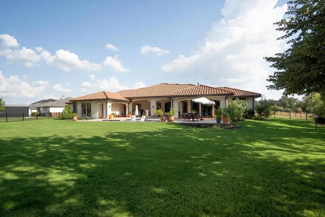 Expansive backyard with mature trees and sprawling green lawn.