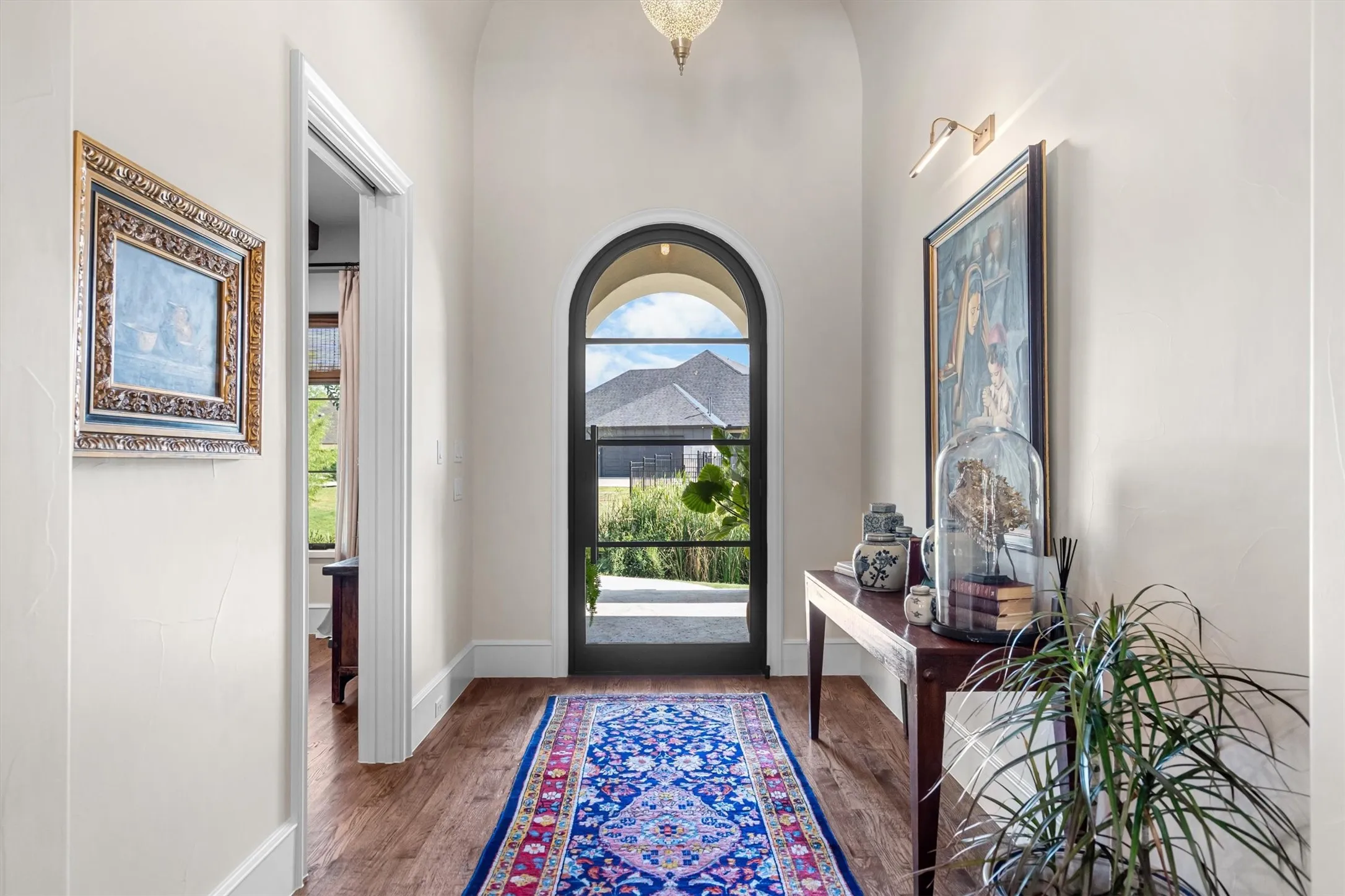 Elegant entry hall with soaring ceilings, arched sightlines straight through to the backyard, and rich wood flooring.