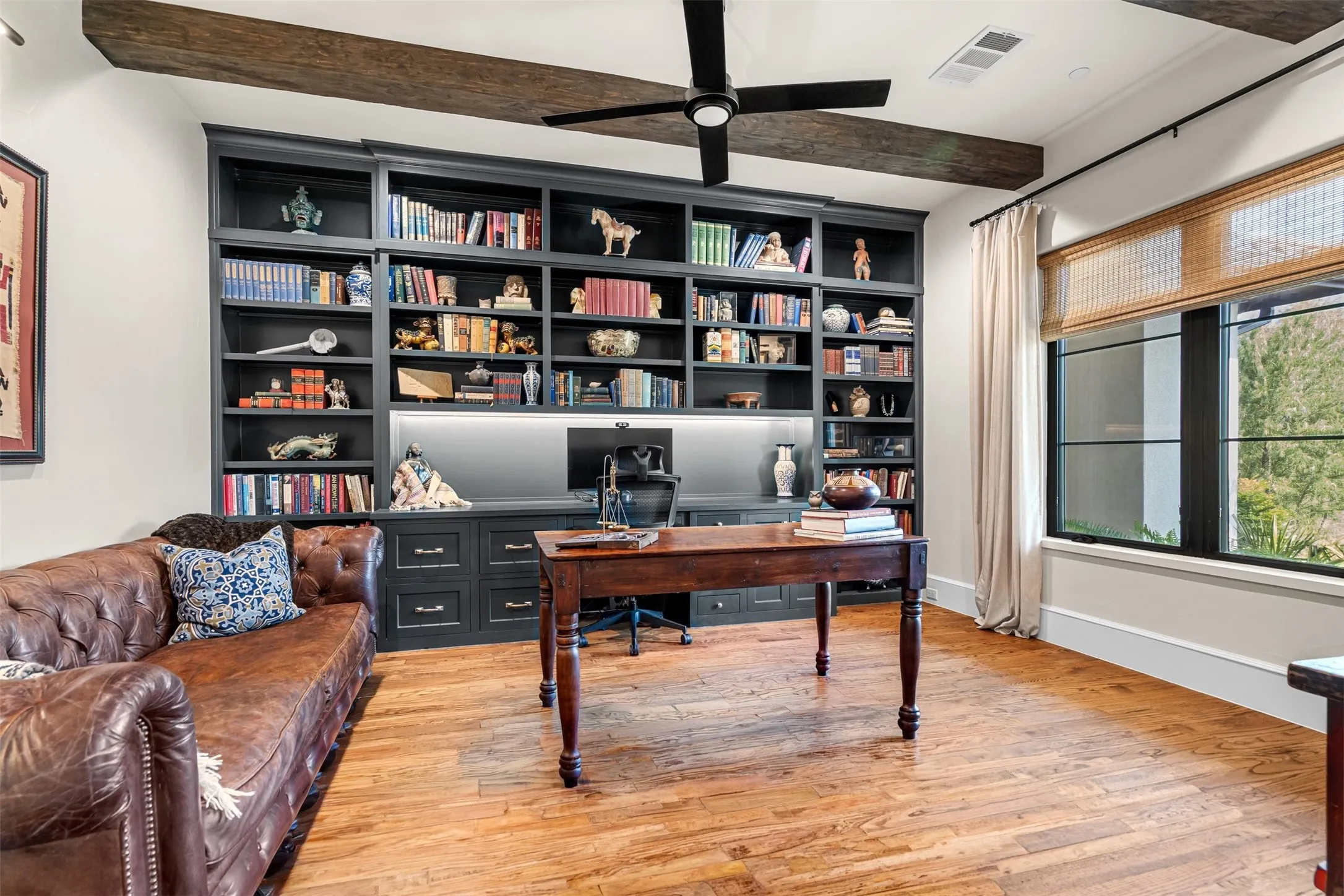 Private study featuring custom built-in bookshelves, leather seating, and a dedicated desk nook — perfect for remote work.