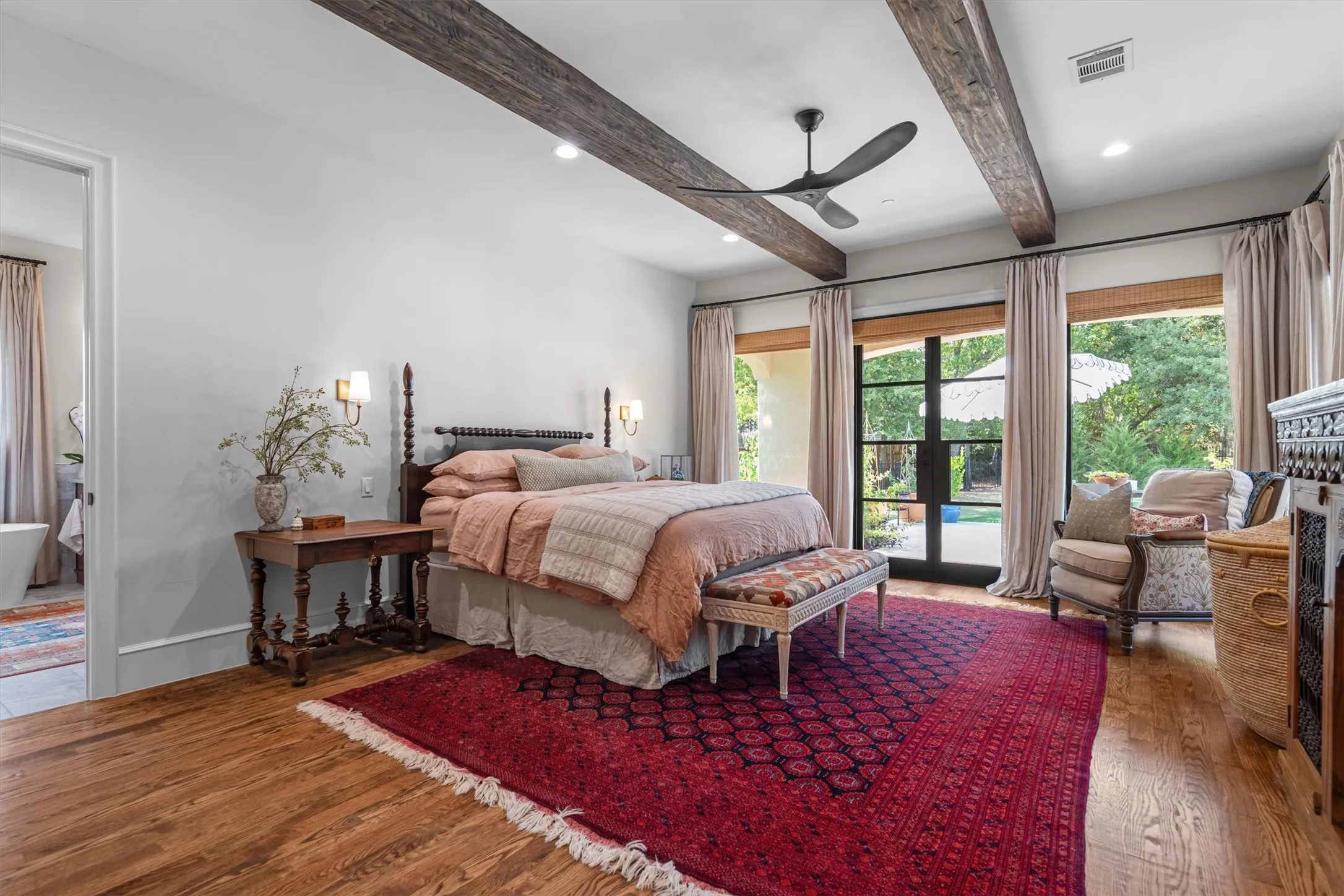 Spacious bedroom with beamed ceilings, private patio access, and abundant natural light.