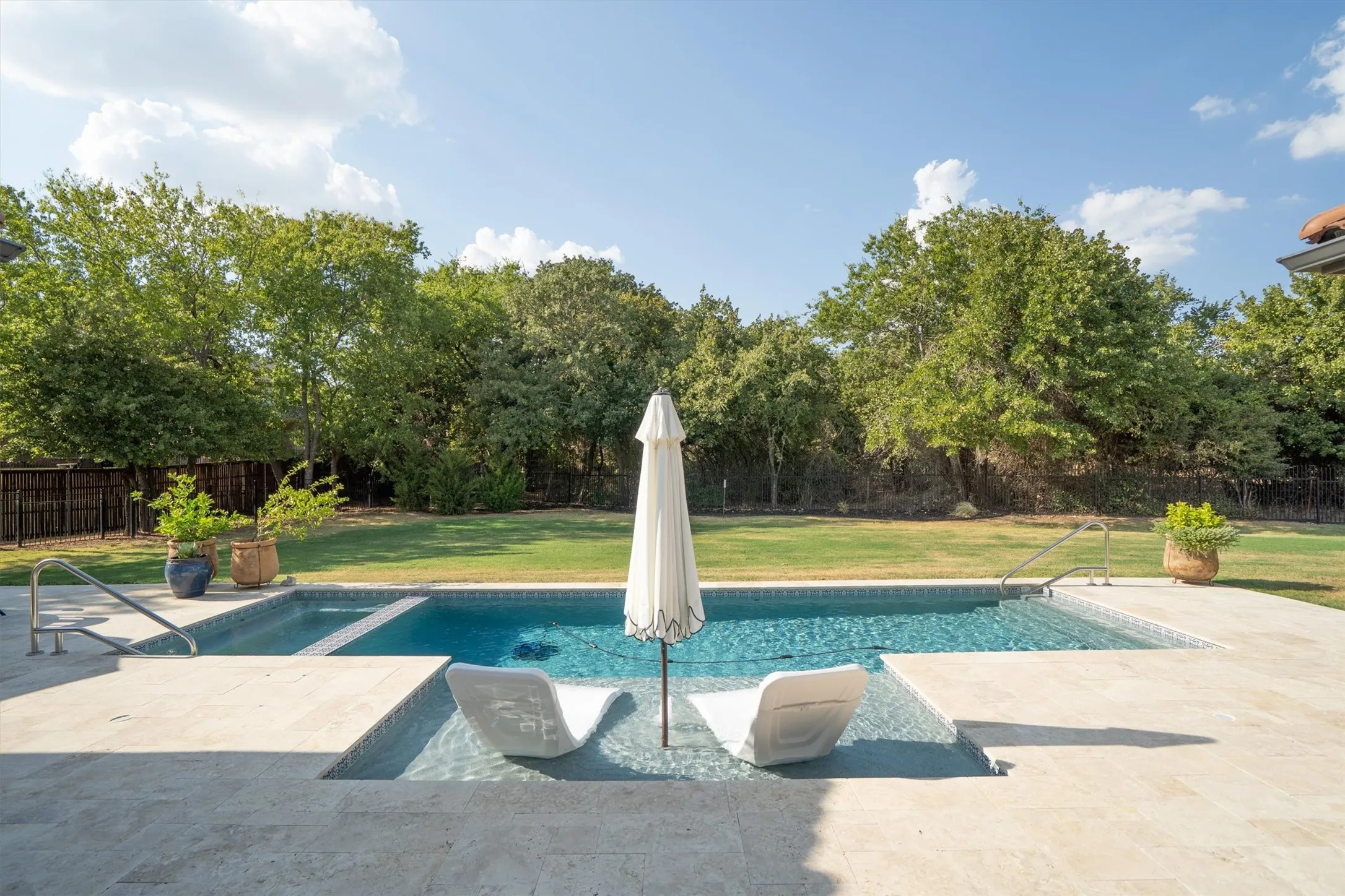 Sparkling pool with lounge seating, surrounded by lush landscaping.