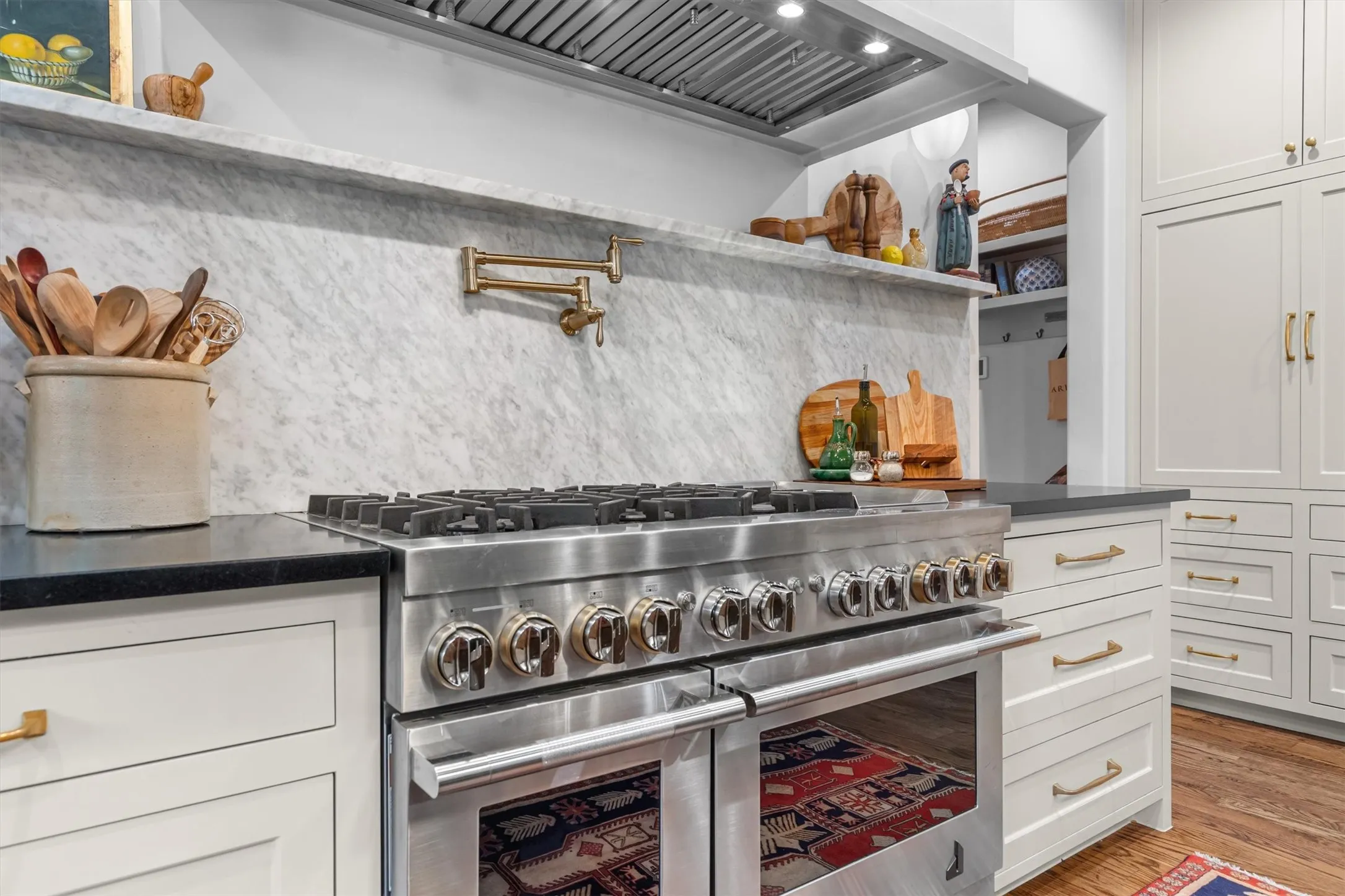 Six-burner gas range with custom hood and open display shelving.