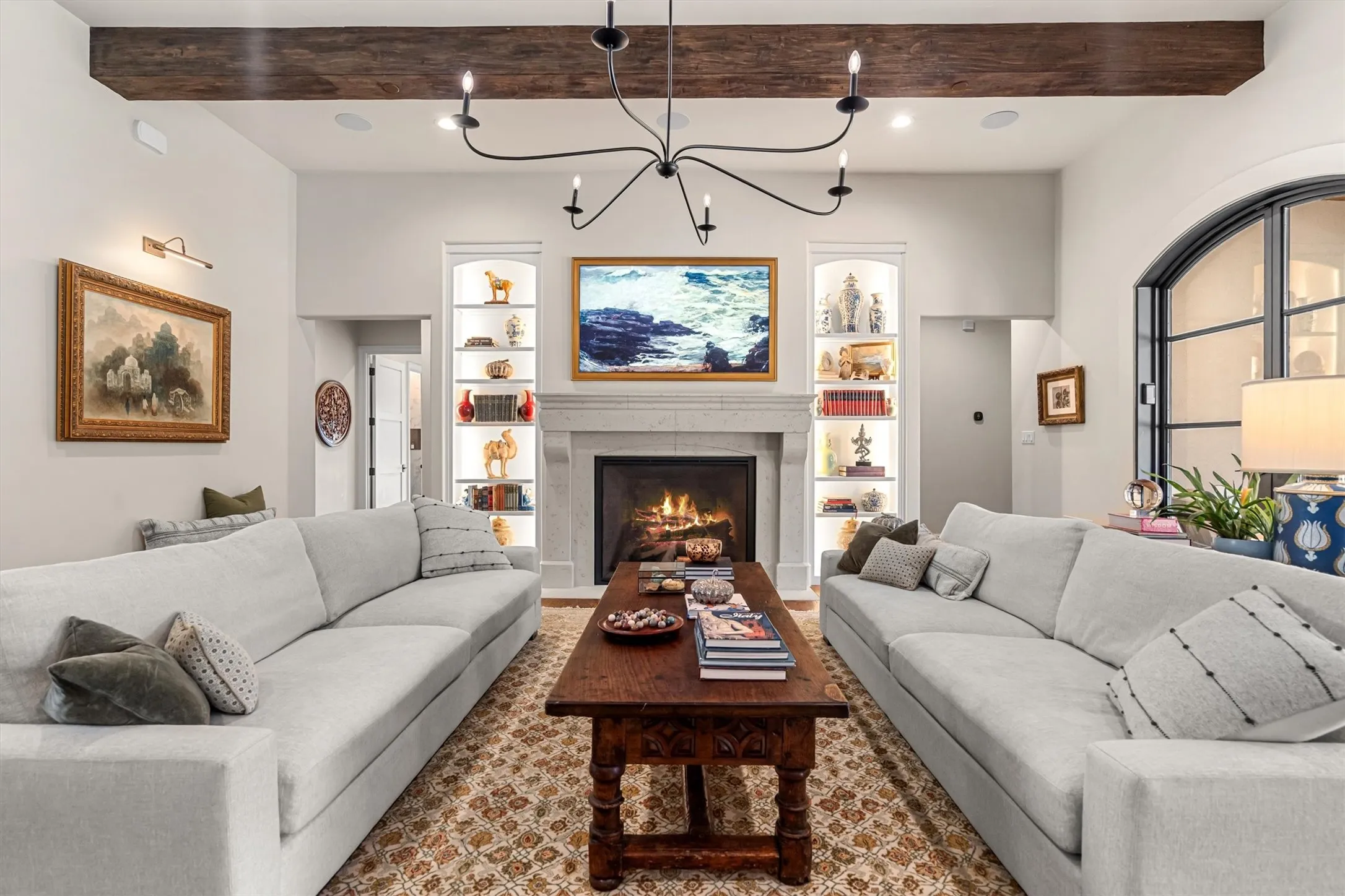 Cozy living room centered on a stone fireplace, oversized sectional seating, and beamed ceilings.
