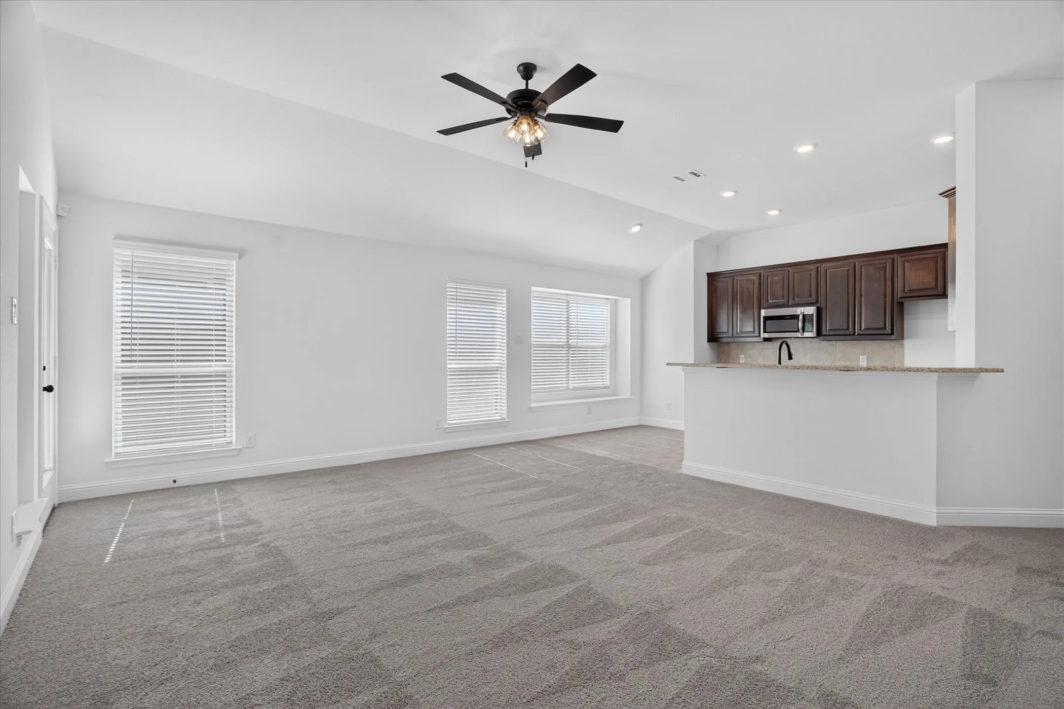 Expansive living area with vaulted ceilings, recessed lighting, and a modern ceiling fan