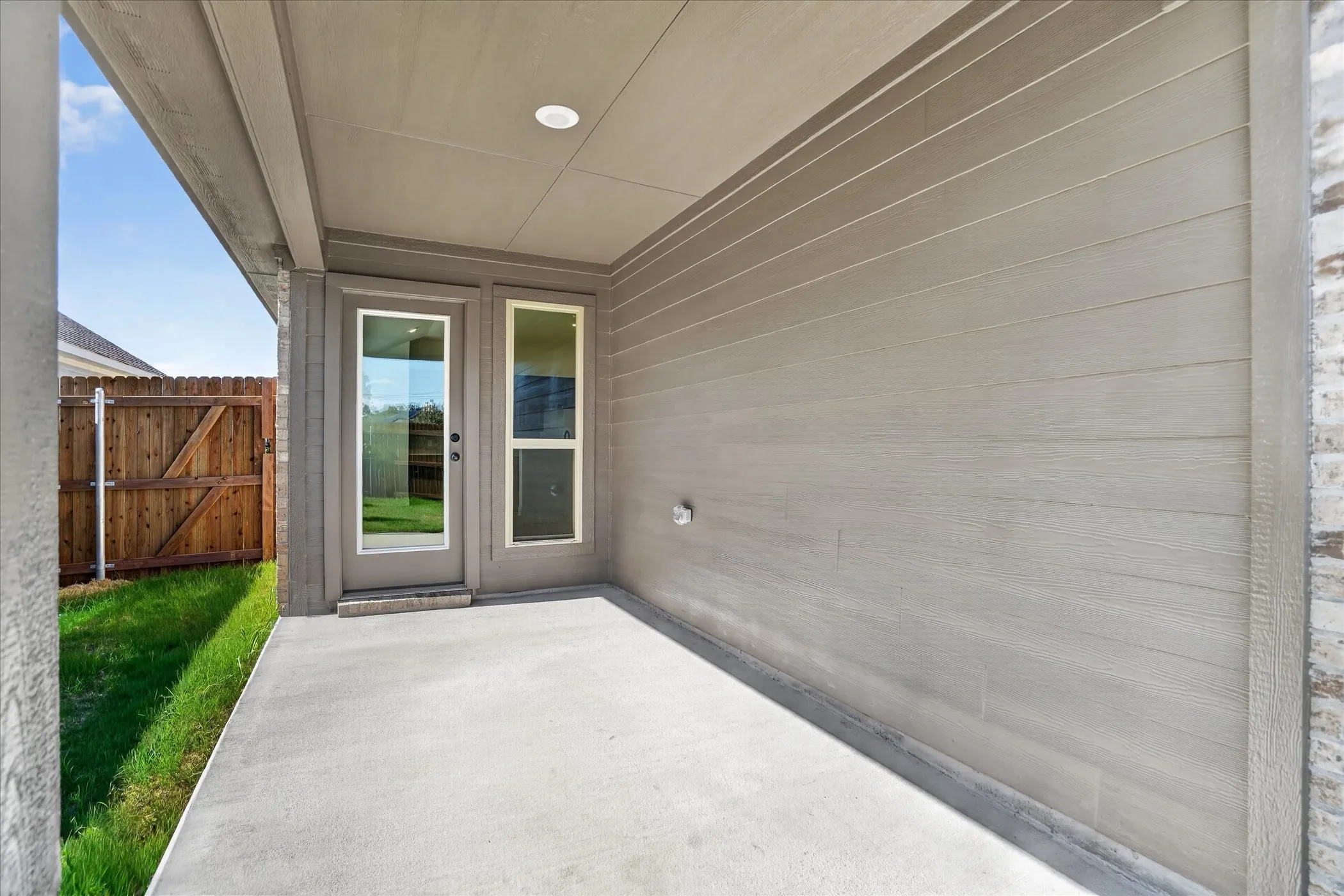 Covered concrete patio with recessed lighting, wood-finish siding, and a full-light glass door