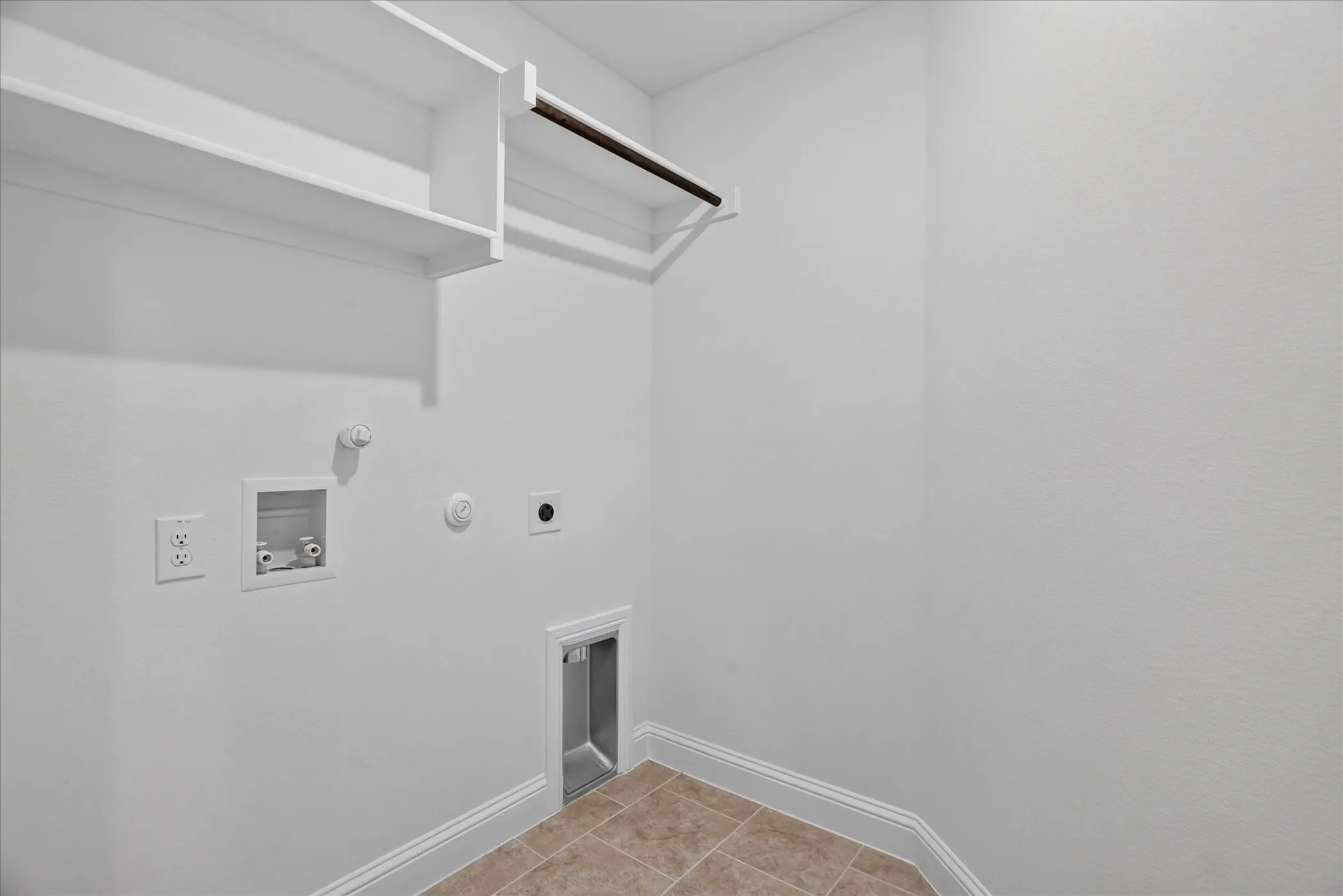 Laundry area with built-in shelving, clothing rod, and tile flooring