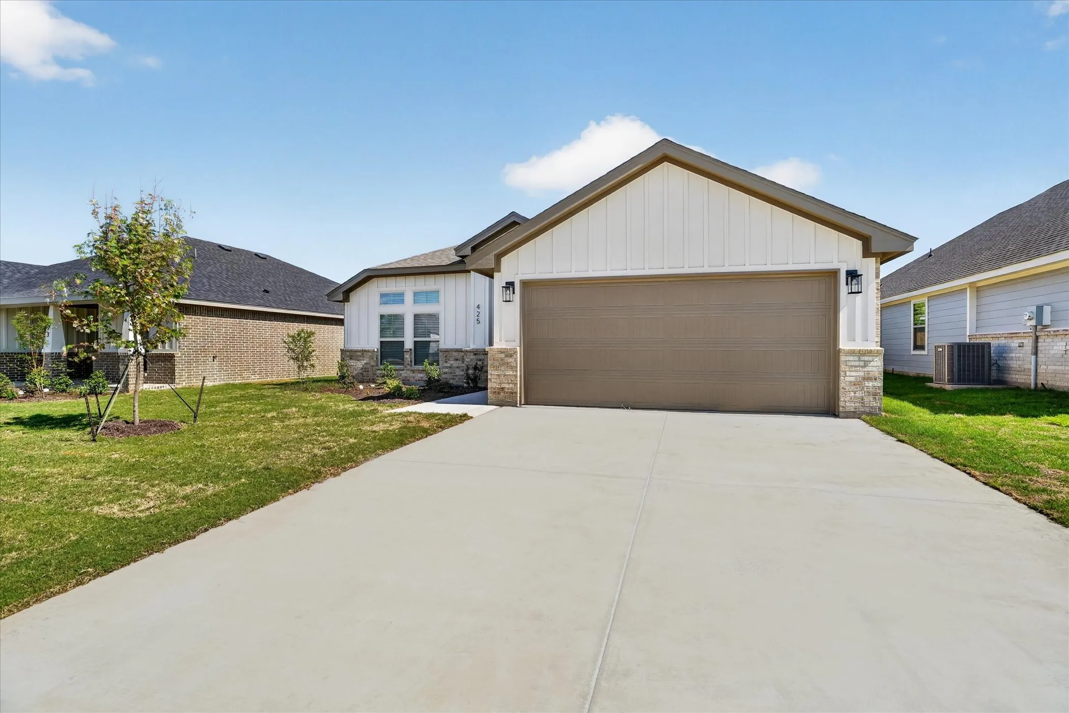 Gable roofline, board and batten siding, stone facade accents, two-car garage, and concrete driveway