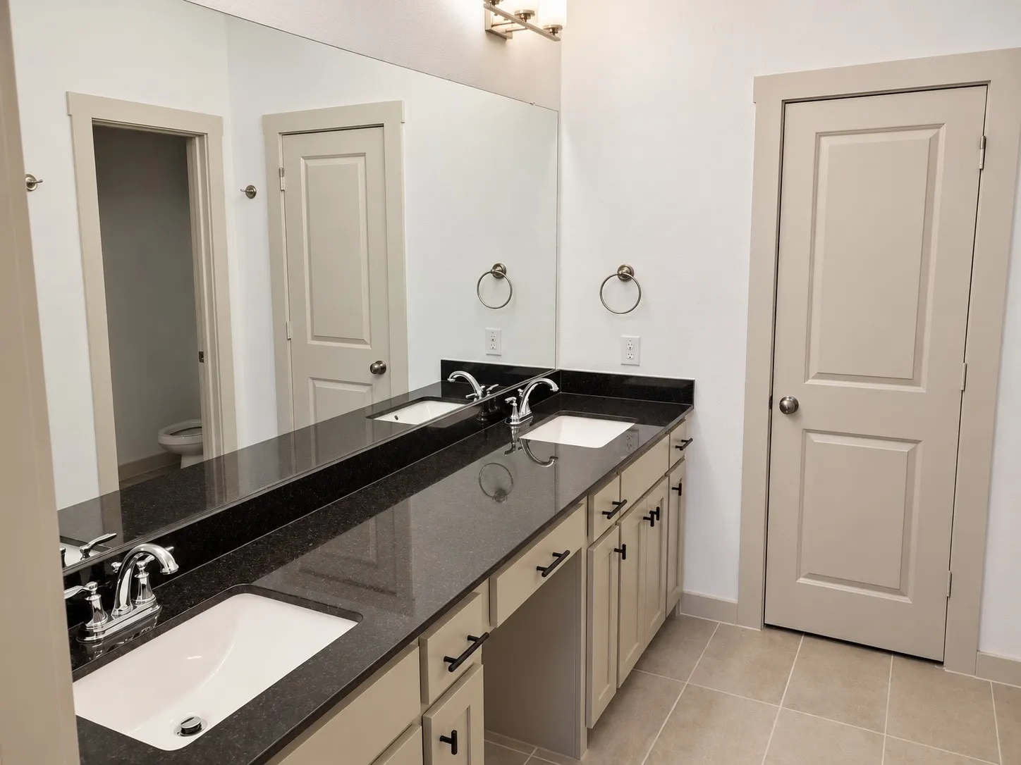 Dual vanity with dark stone countertop and integrated white sinks