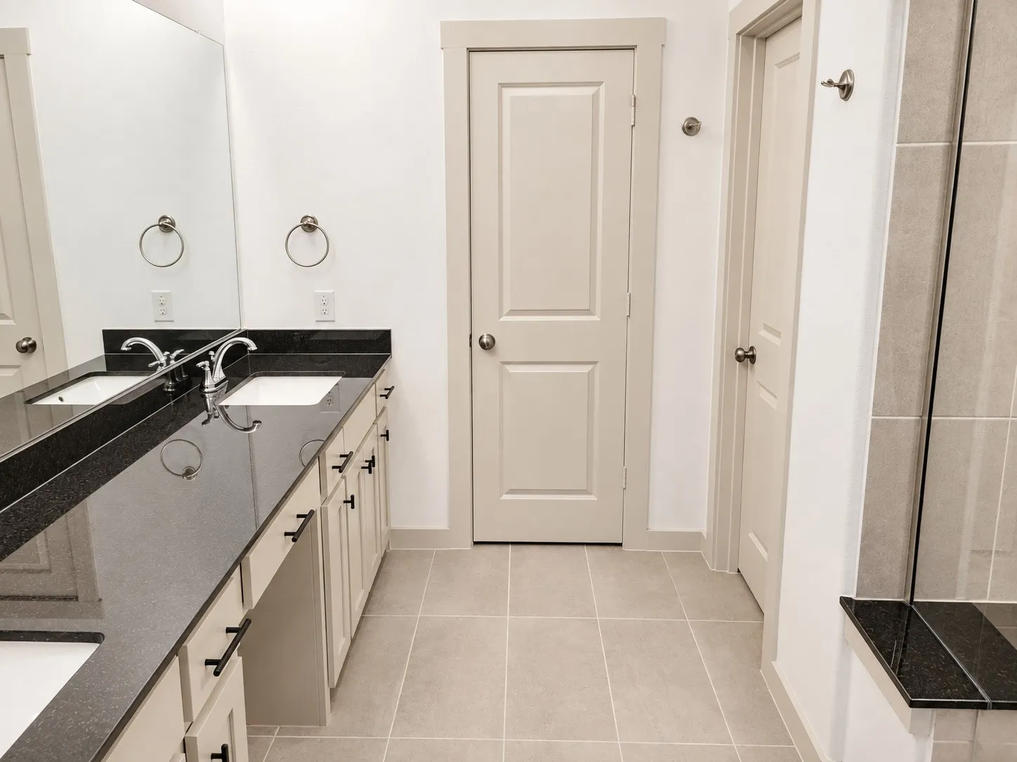 Dual vanity with dark stone countertop, undermount sinks, and chrome fixtures