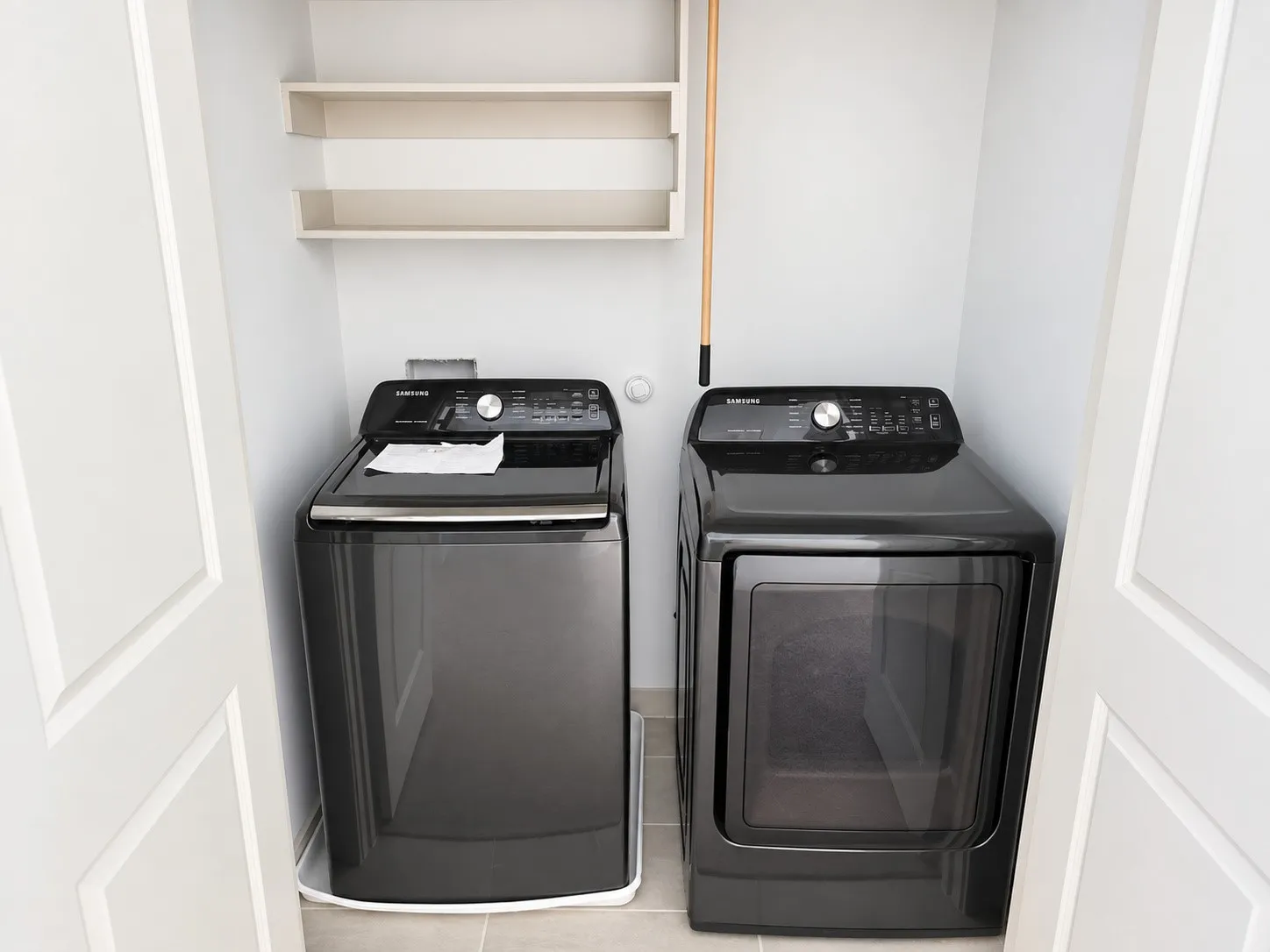 Compact laundry area with a washer and dryer, tile flooring, and integrated wall shelving
