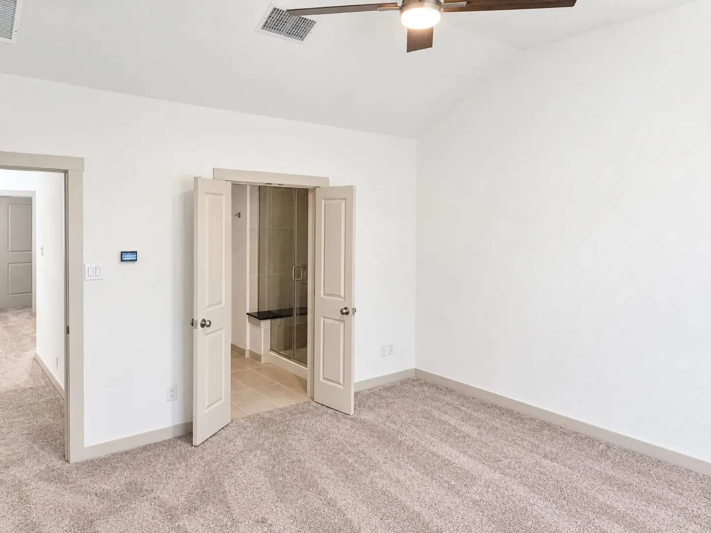 Vaulted ceiling with a ceiling fan, carpeted flooring, and a shower with a built-in bench