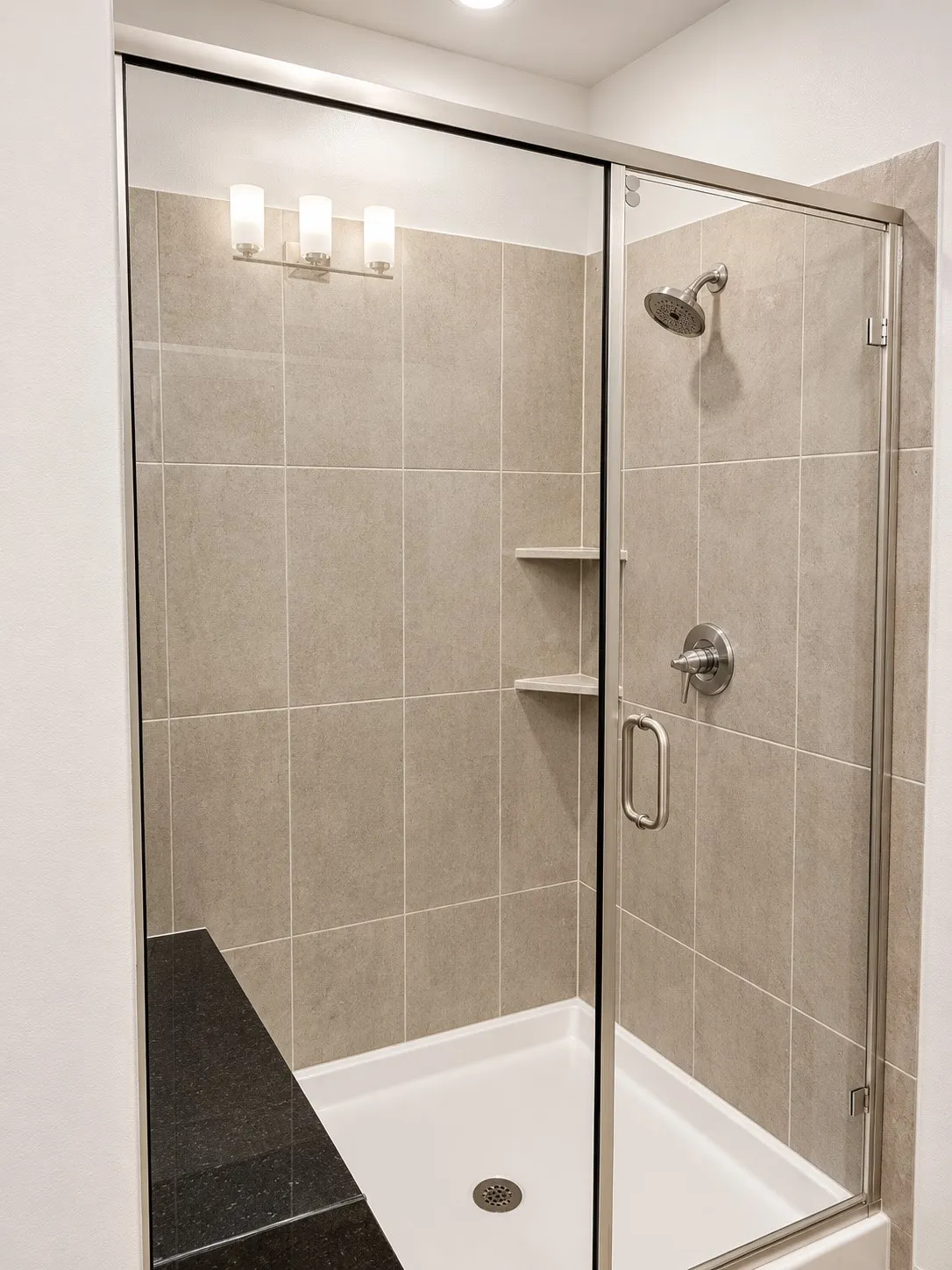 Glass-enclosed shower with a tiled surround, built-in seat, and integrated shelving