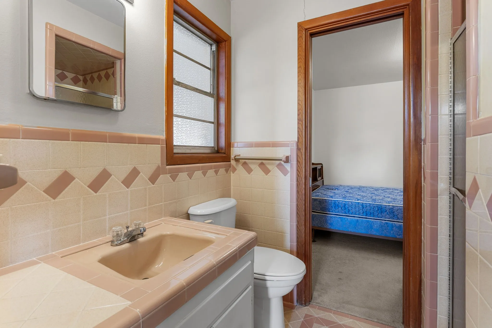Bathroom with tile flooring, tile wainscoting, a vanity with an integrated sink, and a framed mirror