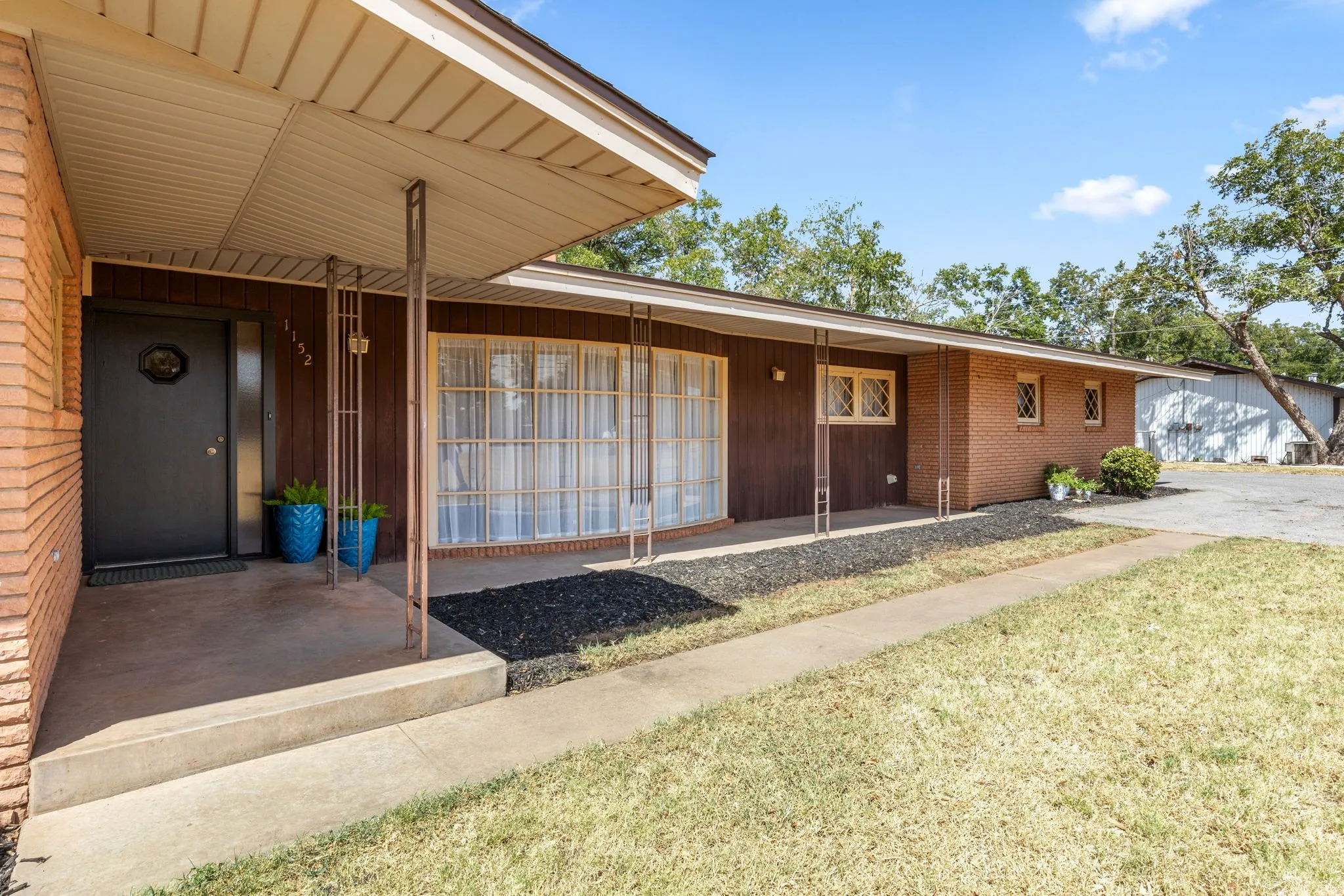 Brick facade with wood-paneled accents, covered entry, and multiple windows