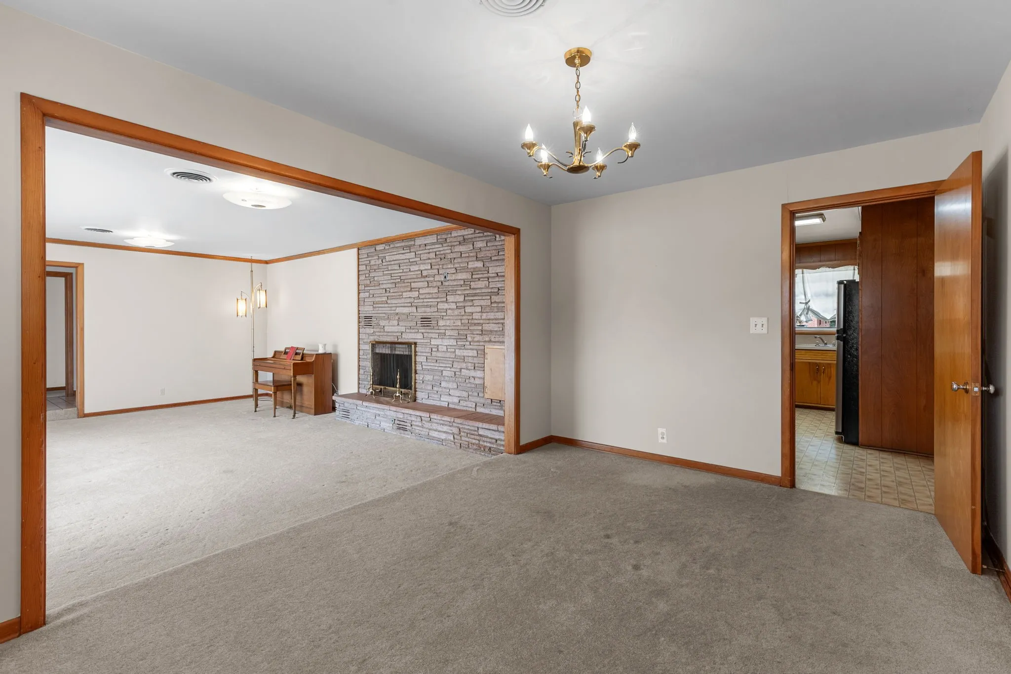 Stone-clad fireplace with hearth, wood trim throughout, and a brass chandelier