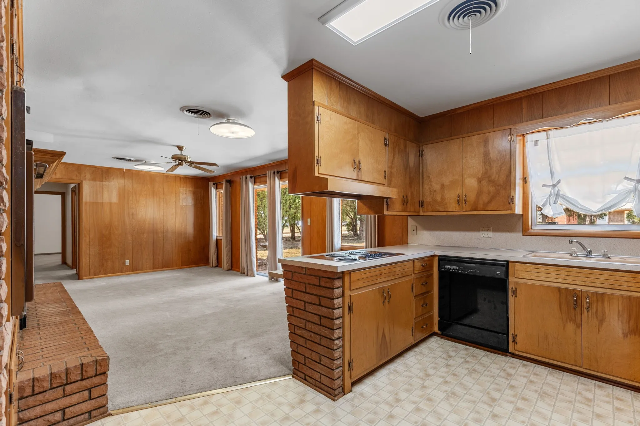 Kitchen featuring wood cabinetry, integrated gas cooktop, black dishwasher, and laminate countertops