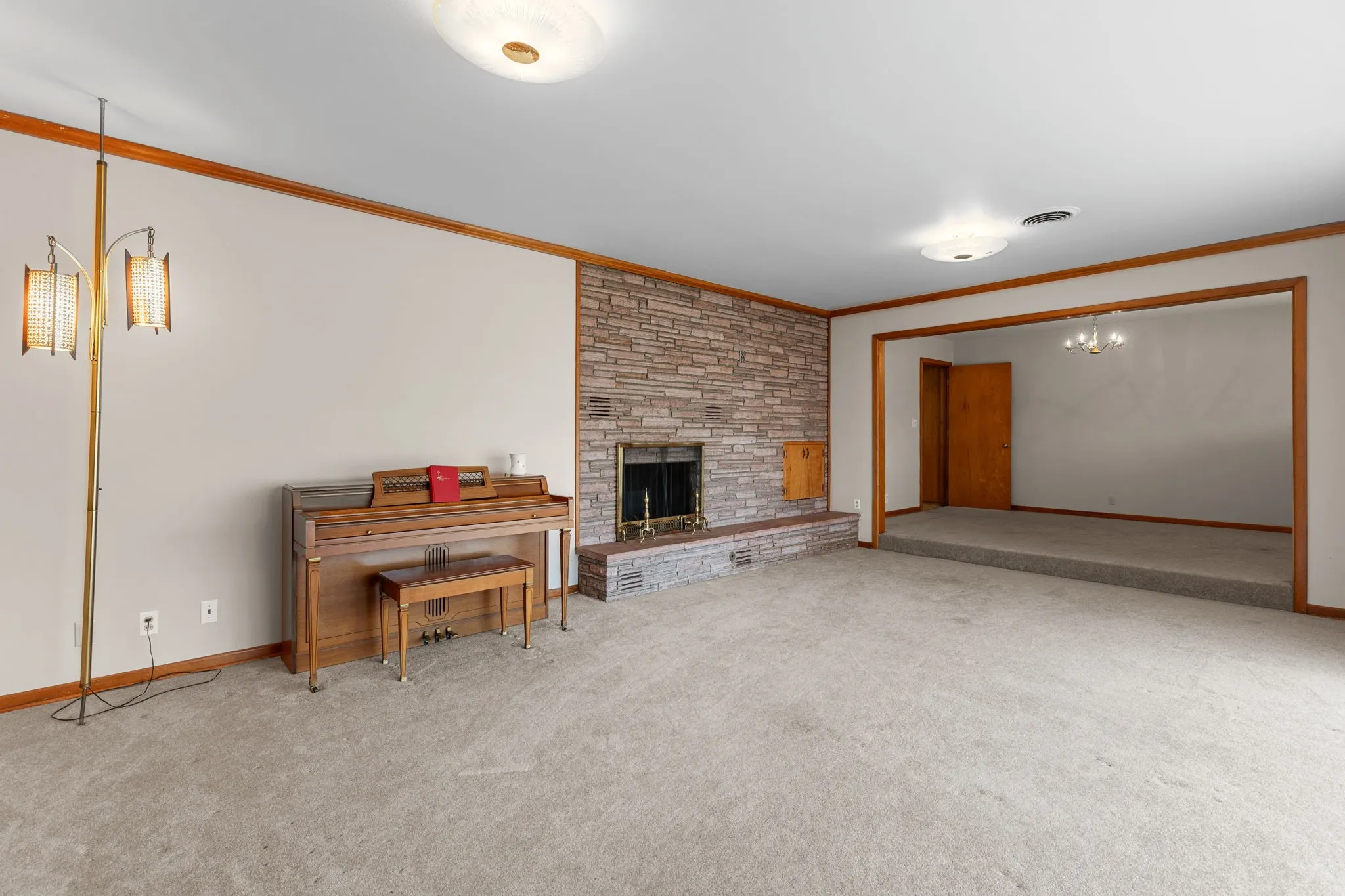 Stone-clad fireplace with a raised hearth, carpeted flooring, and a recessed room with a step-up entry