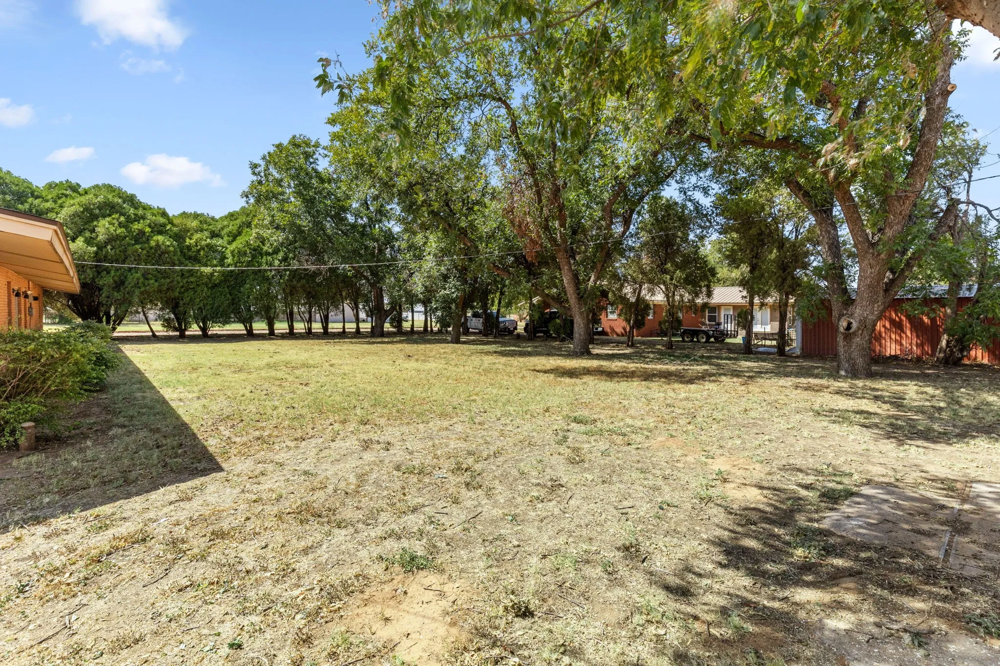 Expansive outdoor space featuring mature trees and a substantial grassy area