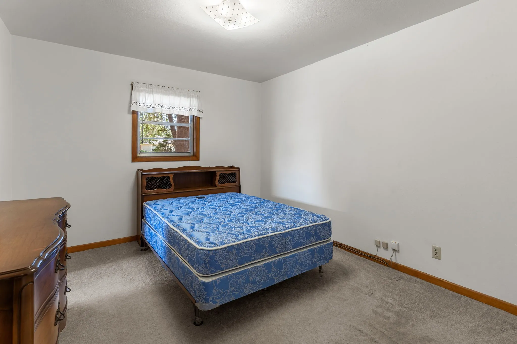 Carpeted flooring with a window featuring wood trim, and a ceiling-mounted light fixture