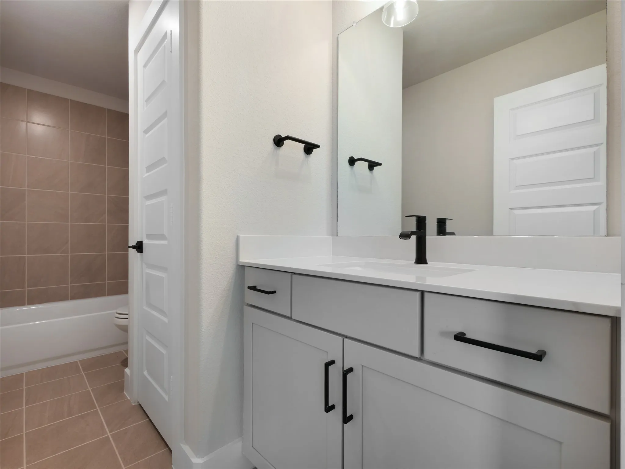 Bedroom 3 ensuite bath White vanity with black hardware, white countertop, integrated sink, and linen closet.