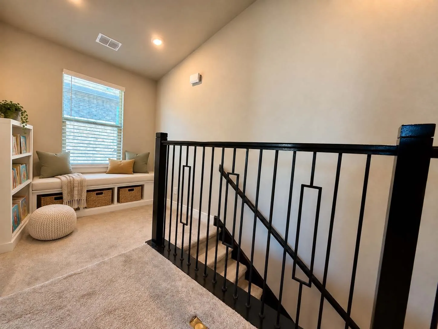 Virtually staged by AI. Built-in window seat with integrated storage, white built-in shelving, black metal staircase railing, and recessed lighting
