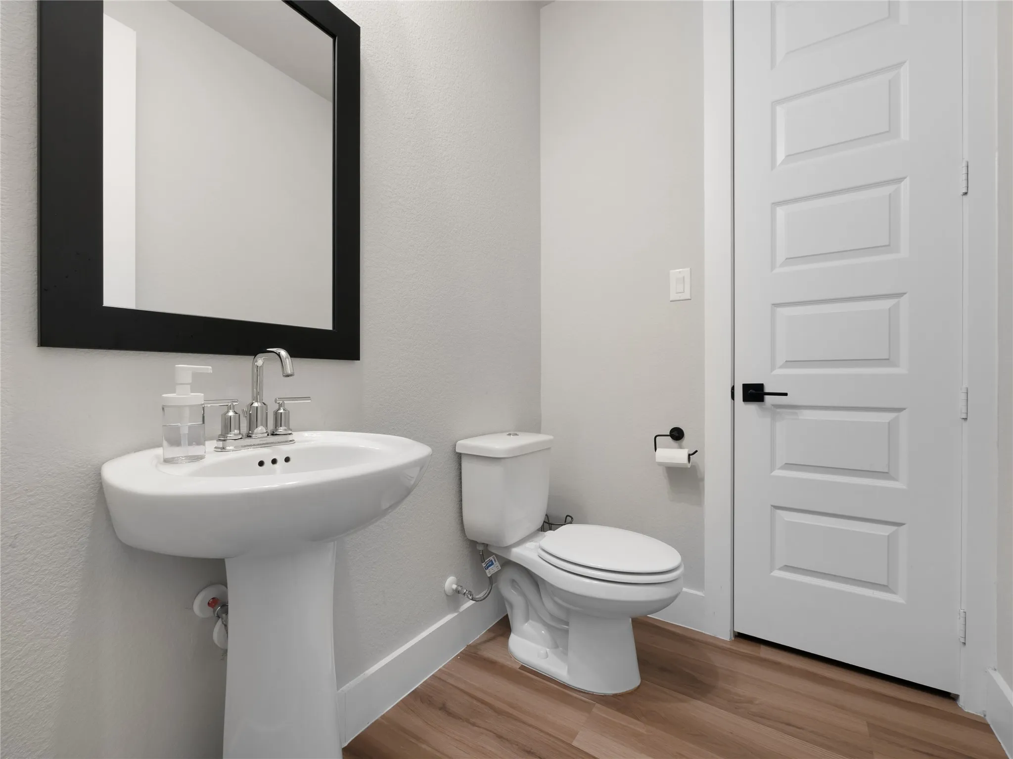 Half Bath with pedestal sink with chrome faucet, framed mirror, and linen closet.