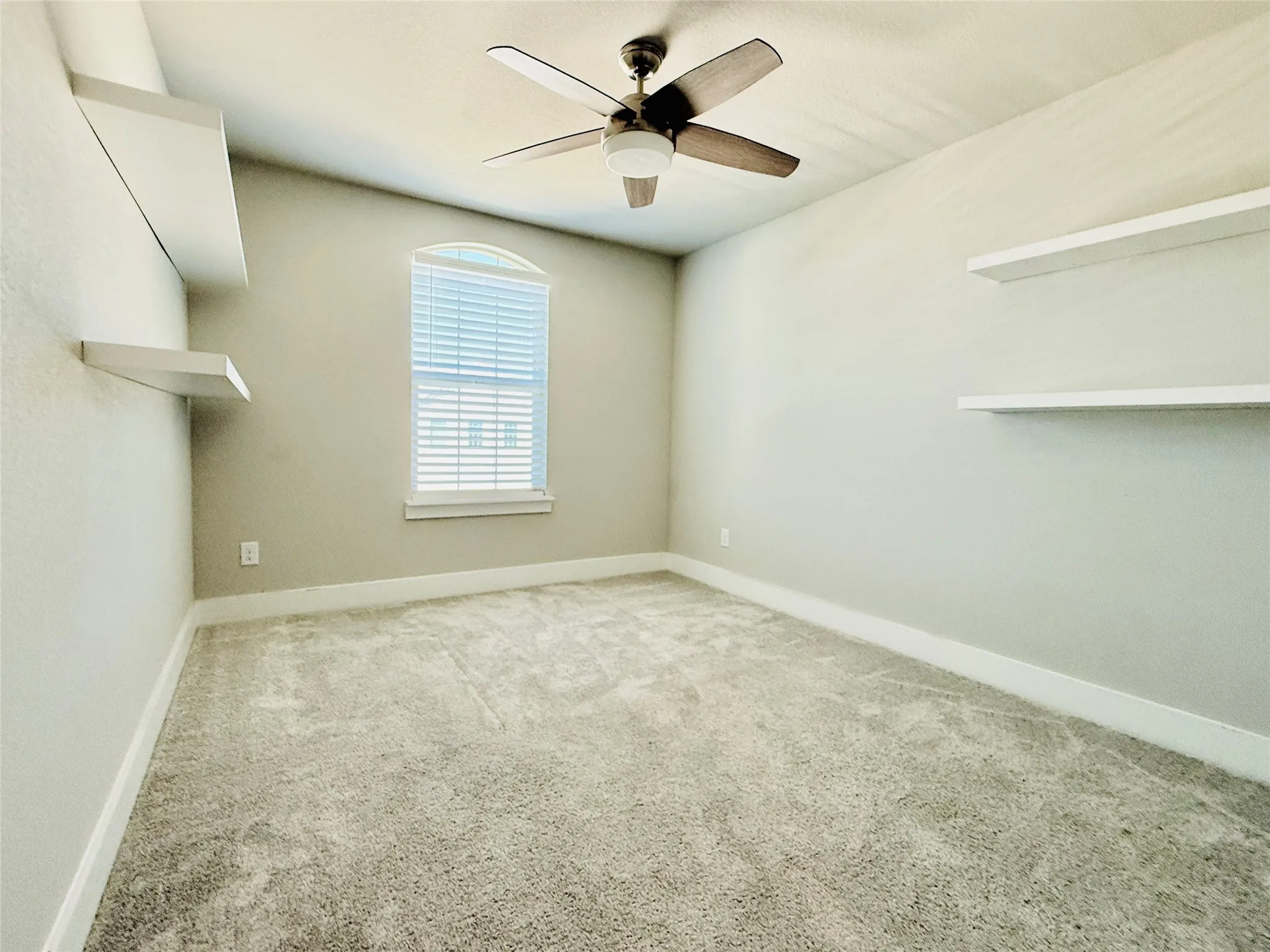 Bedroom 2 featuring a ceiling fan, a window with blinds, and built-in floating shelves