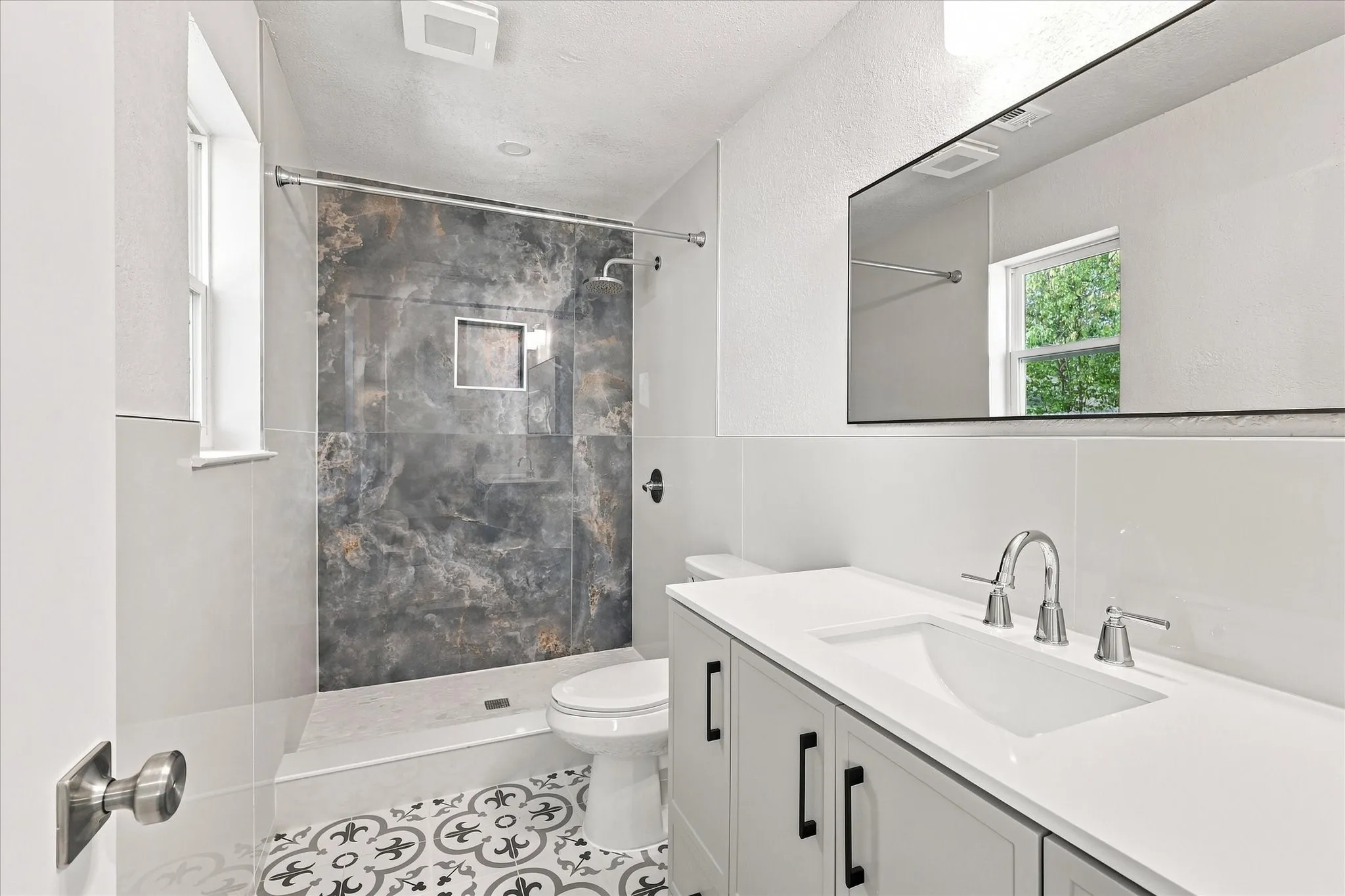 Walk-in shower with a decorative tile accent wall and built-in niche