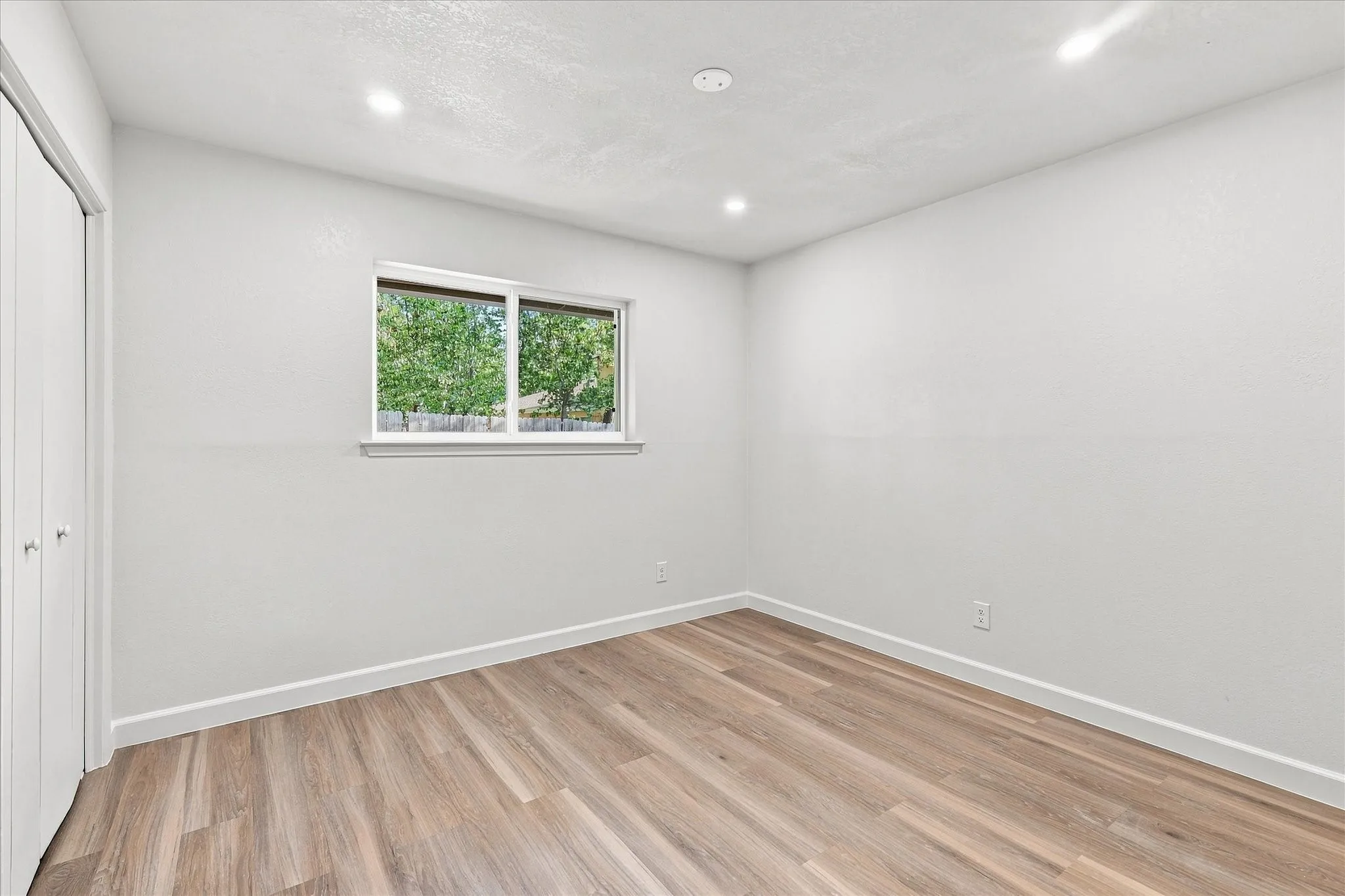 Wood-finish flooring, white walls, and recessed lighting