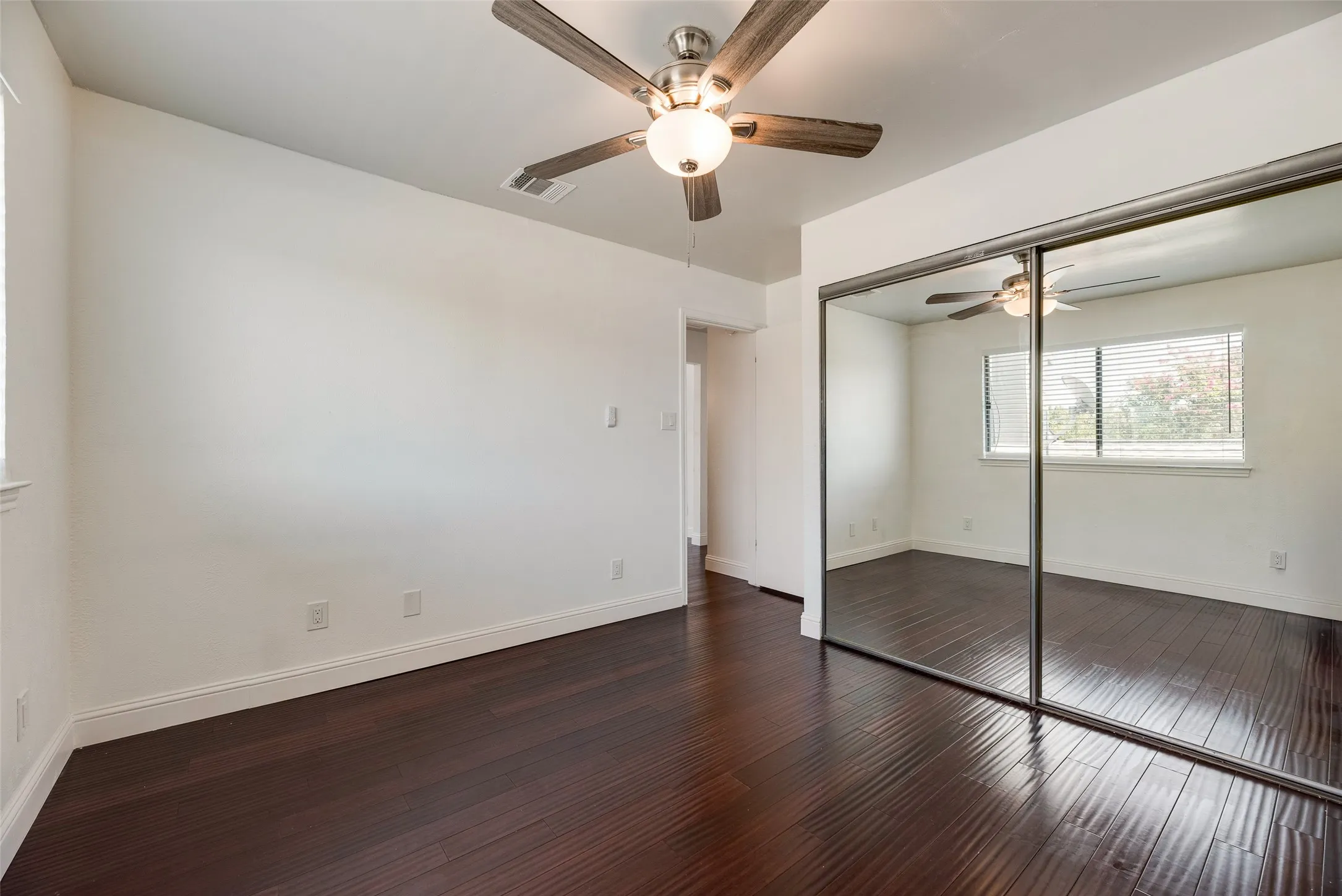 Dark wood-finish flooring, white walls, and a ceiling fan with light fixture