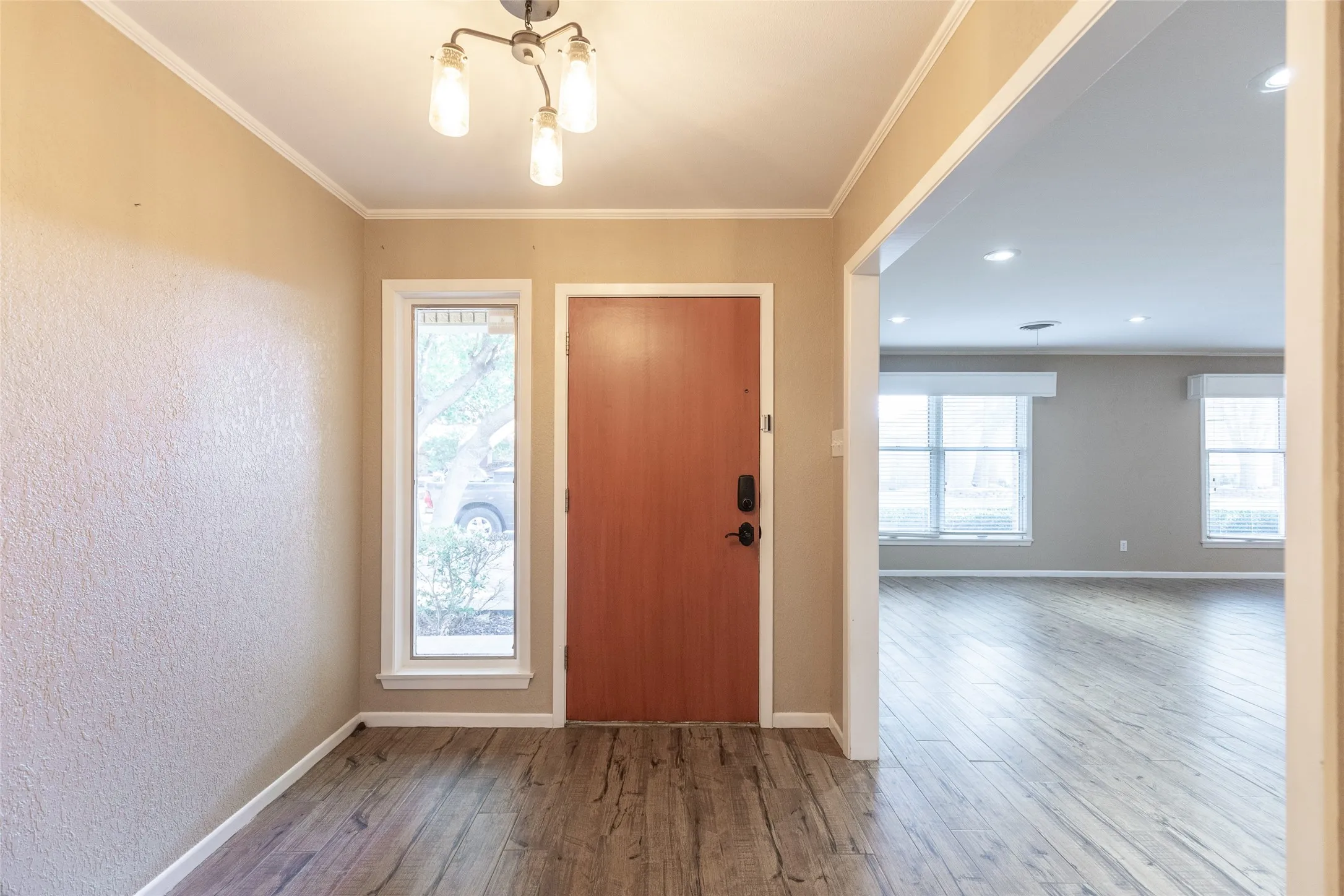 Entryway featuring wood-finish flooring, a modern chandelier with four lights, and an adjacent vertical window