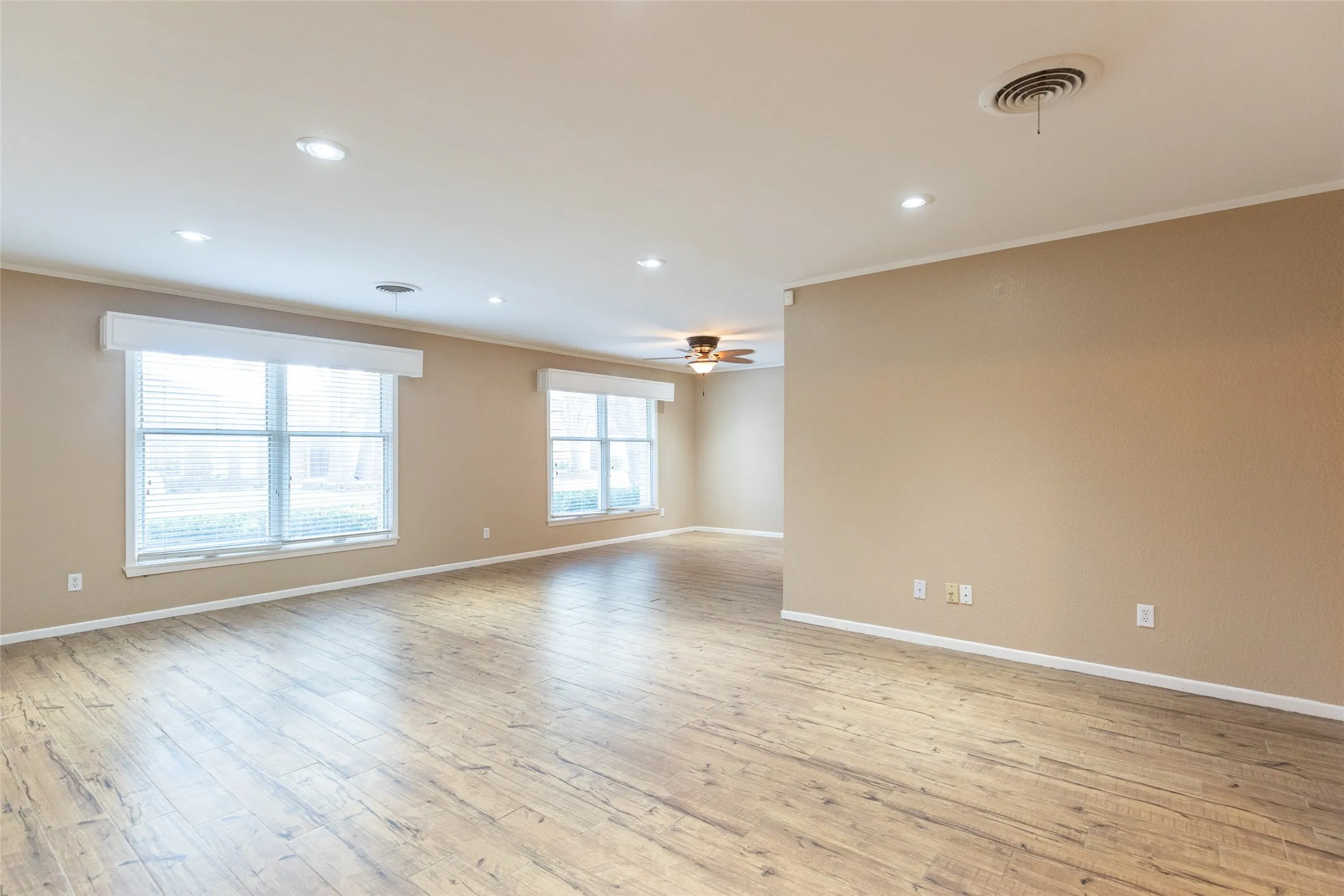 Recessed lighting, wood-finish flooring, multiple windows with blinds, ceiling fan, neutral wall tones