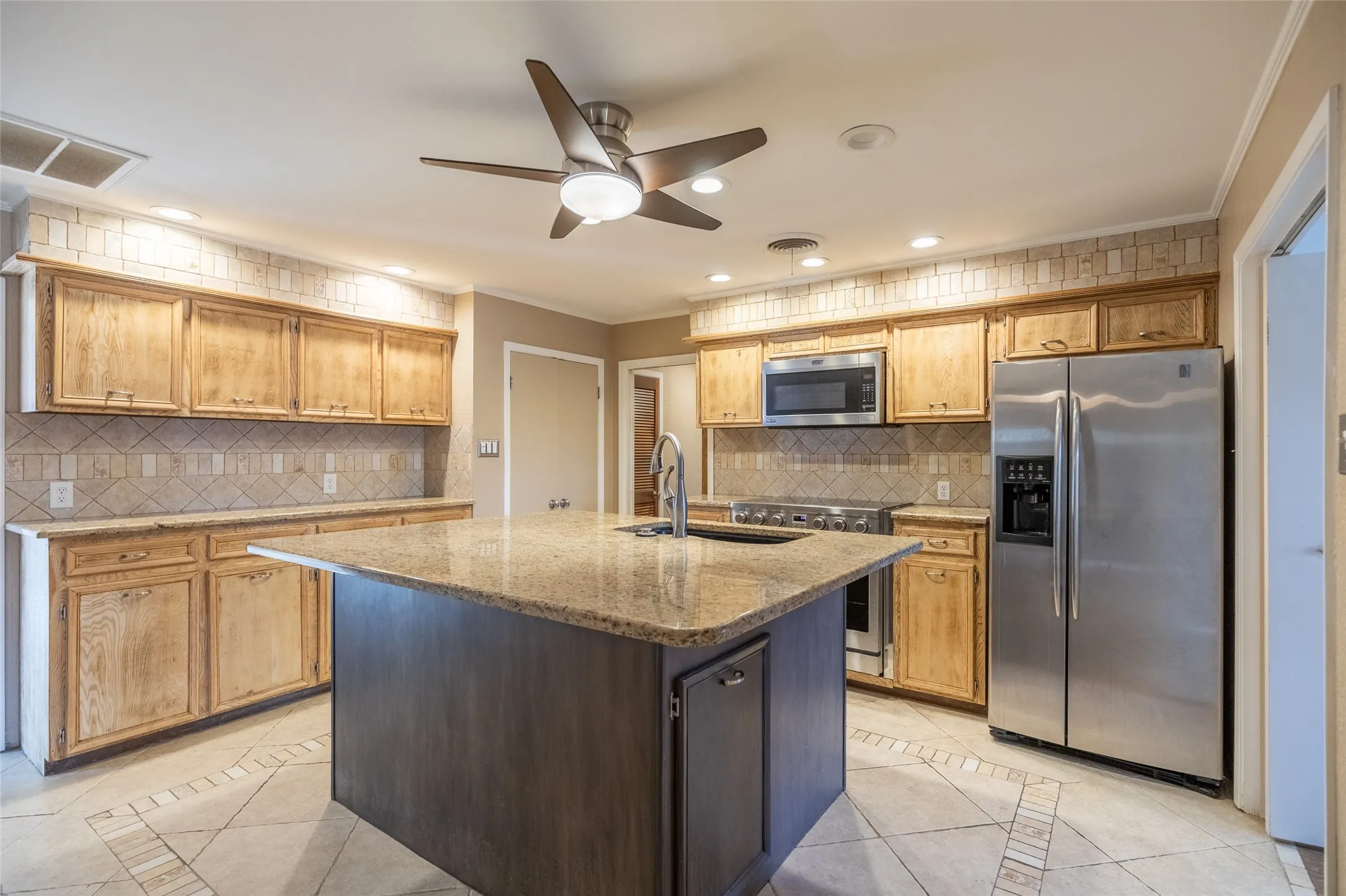 Kitchen featuring wood cabinetry, stainless steel appliances, a center island with sink, granite countertops, and recessed lighting