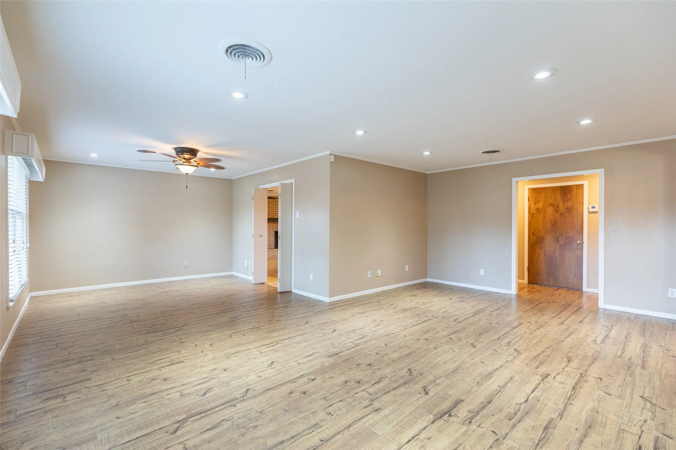 Spacious room featuring wood-finish flooring, recessed lighting, and a ceiling fan