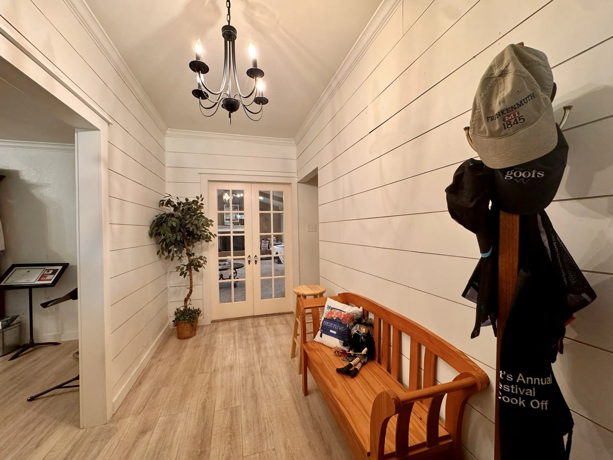 Front door entrance with vaulted ceilings and chandelier. Room to store your items. Decorative french doors lead to the living room.