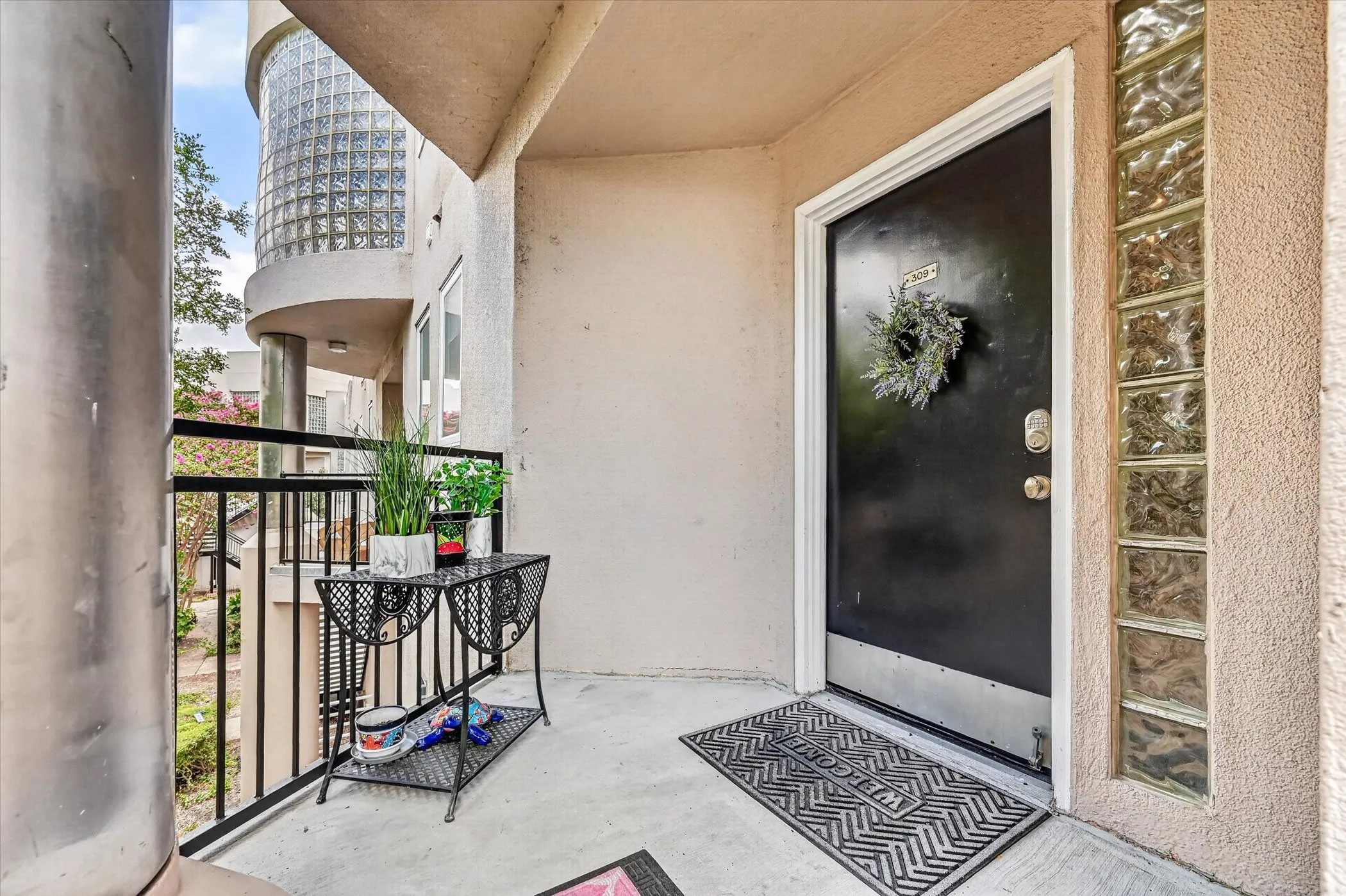 Entry with a black door, clear glass block window, concrete flooring, and a black wrought iron railing