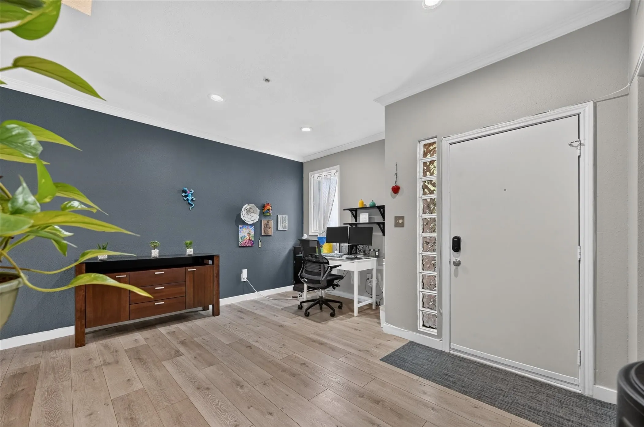 Wood-finish flooring, recessed ceiling lighting, and a front entry door with a glass block sidelight